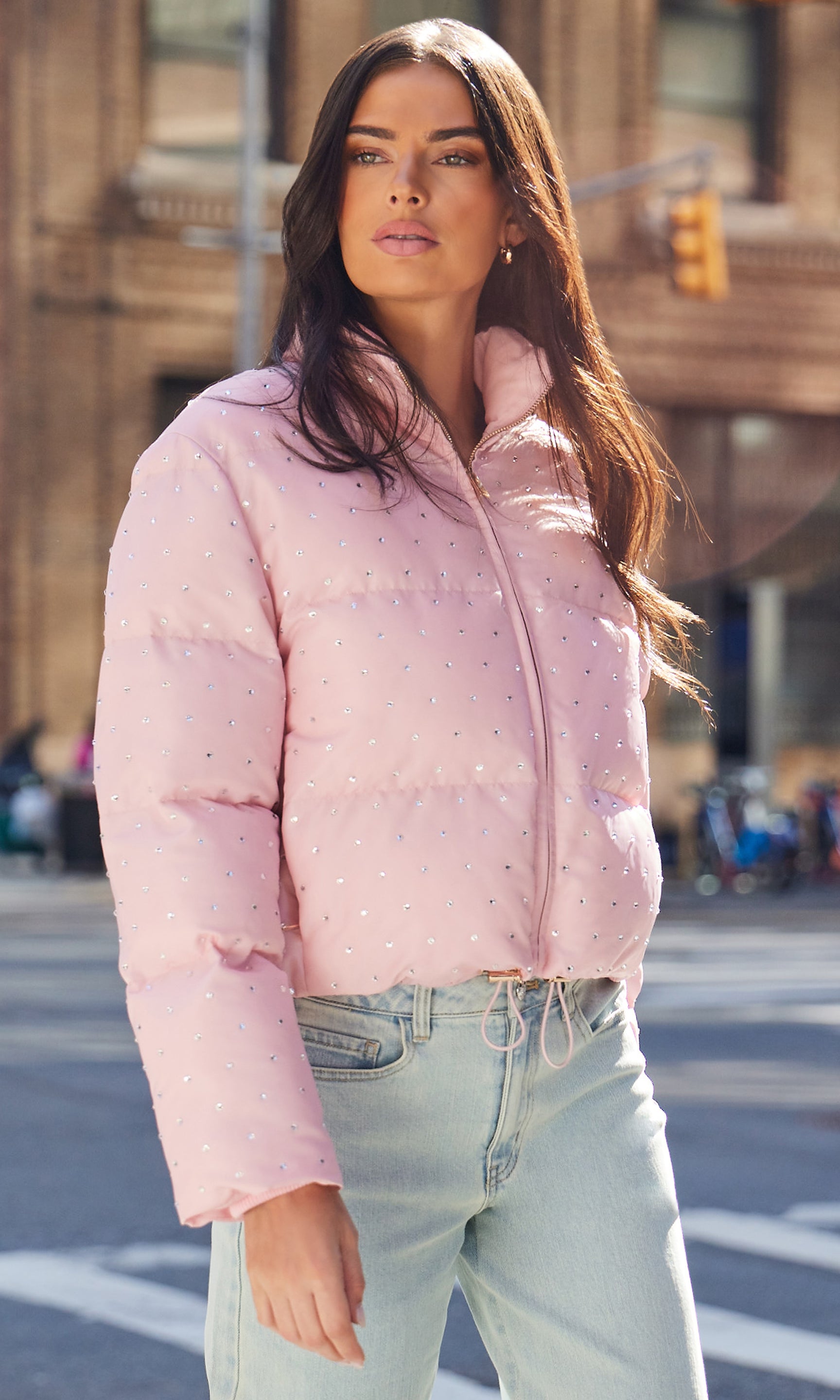 Woman wearing a pink puffer jacket on a city street