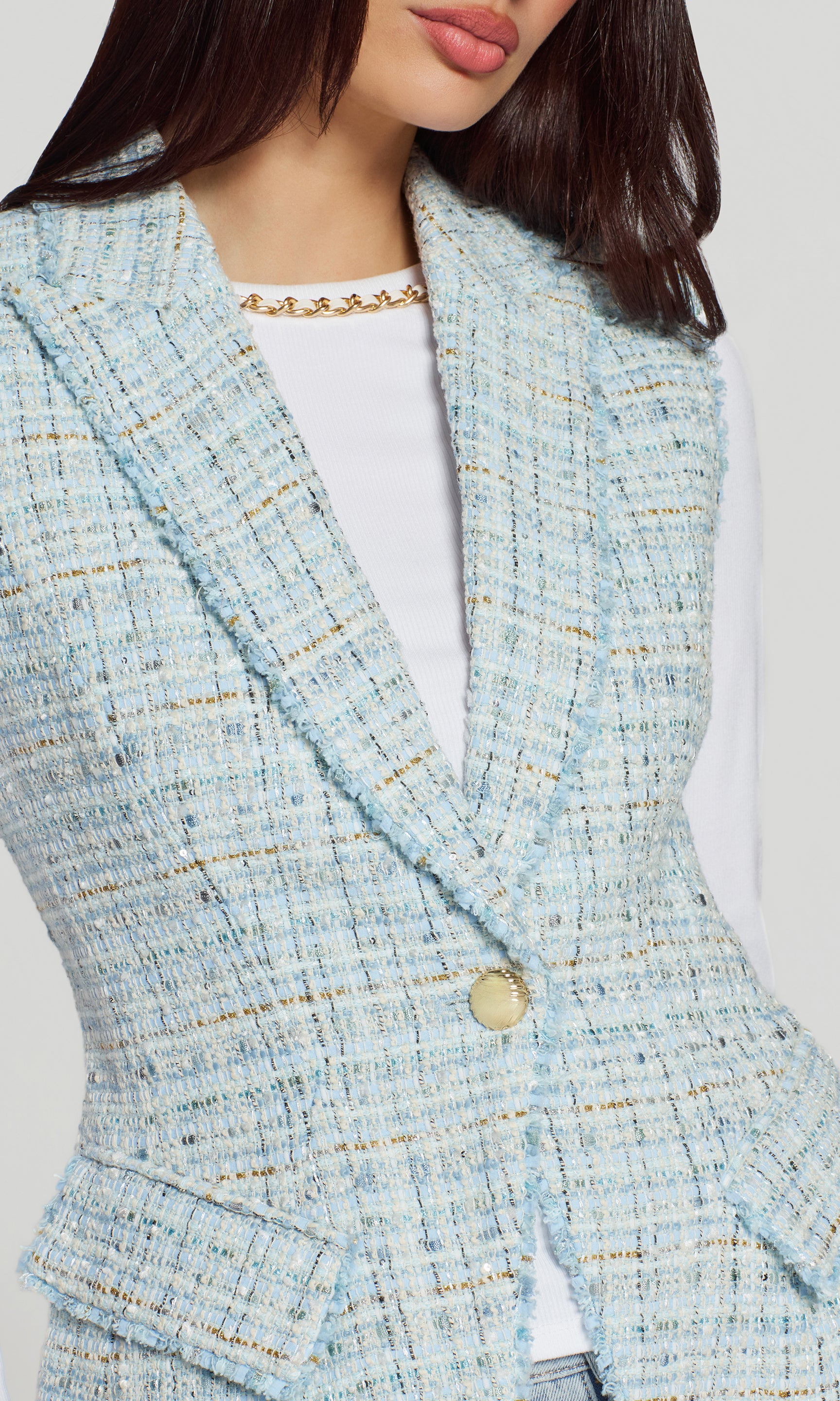 Close-up of light blue tweed blazer worn by a person on a white background