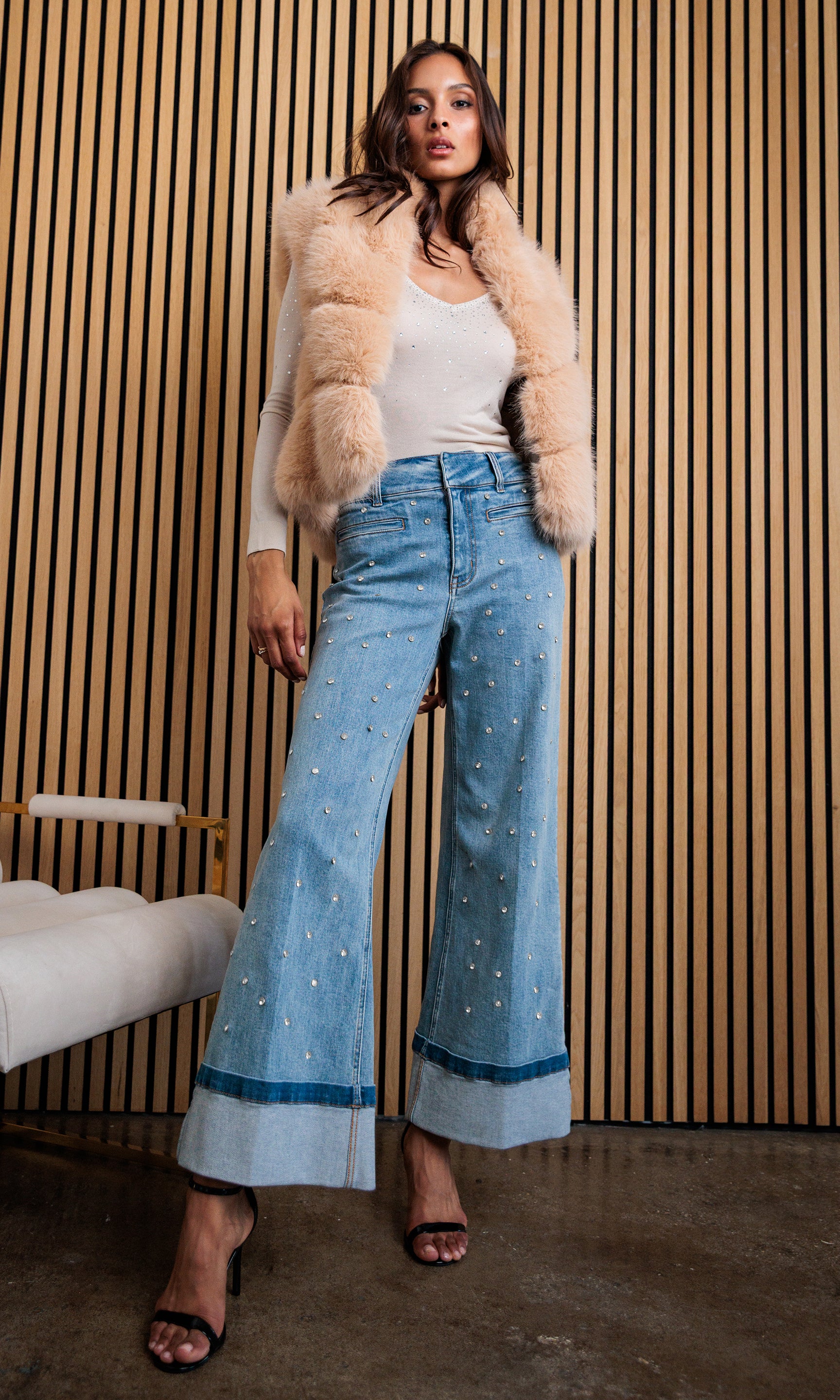 Full body front view of Rosario Faux Fur Vest in toffee, paired with a cream top and wide-leg blue jeans.