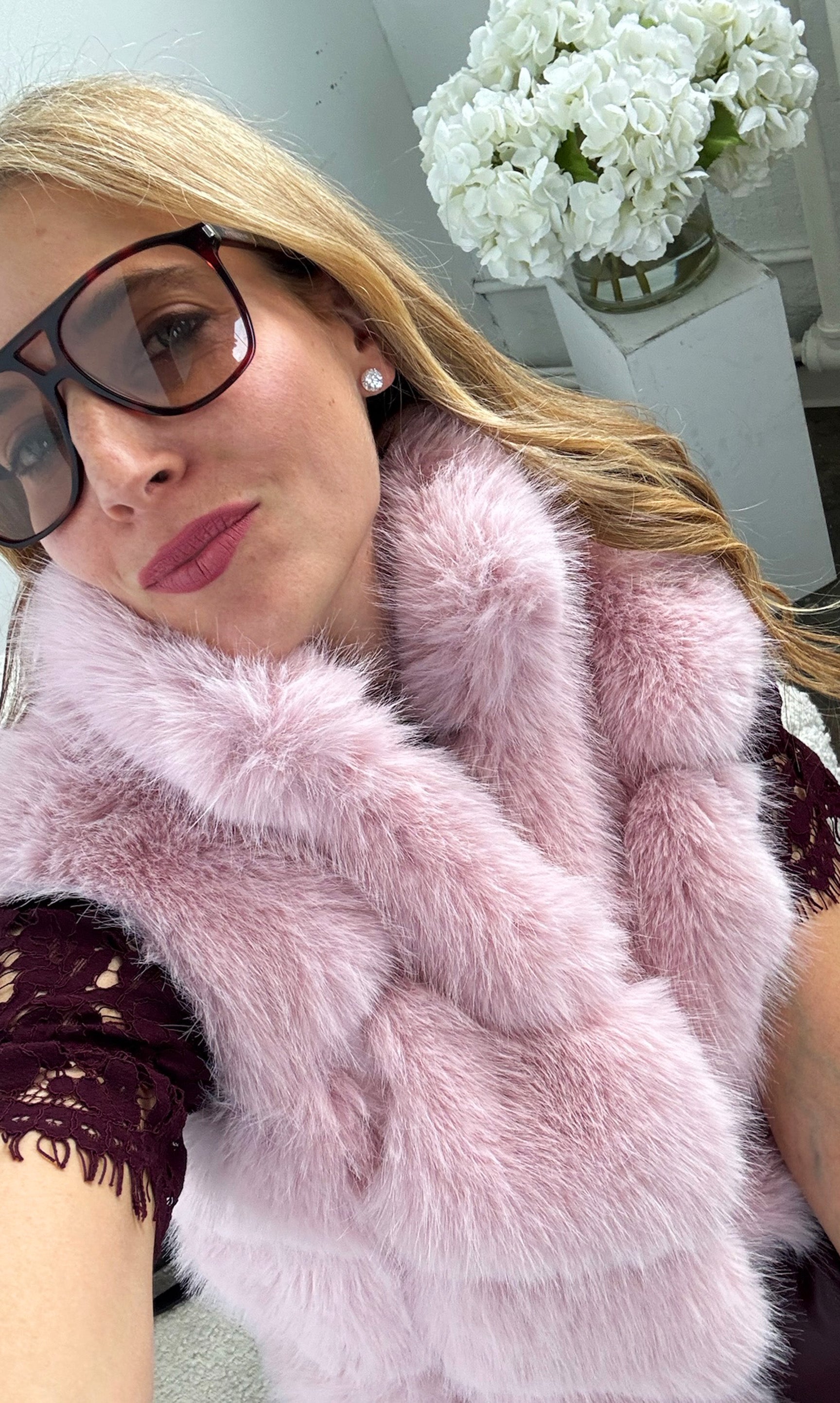 Our founder Roni wearing a pink fur vest with a blurred background