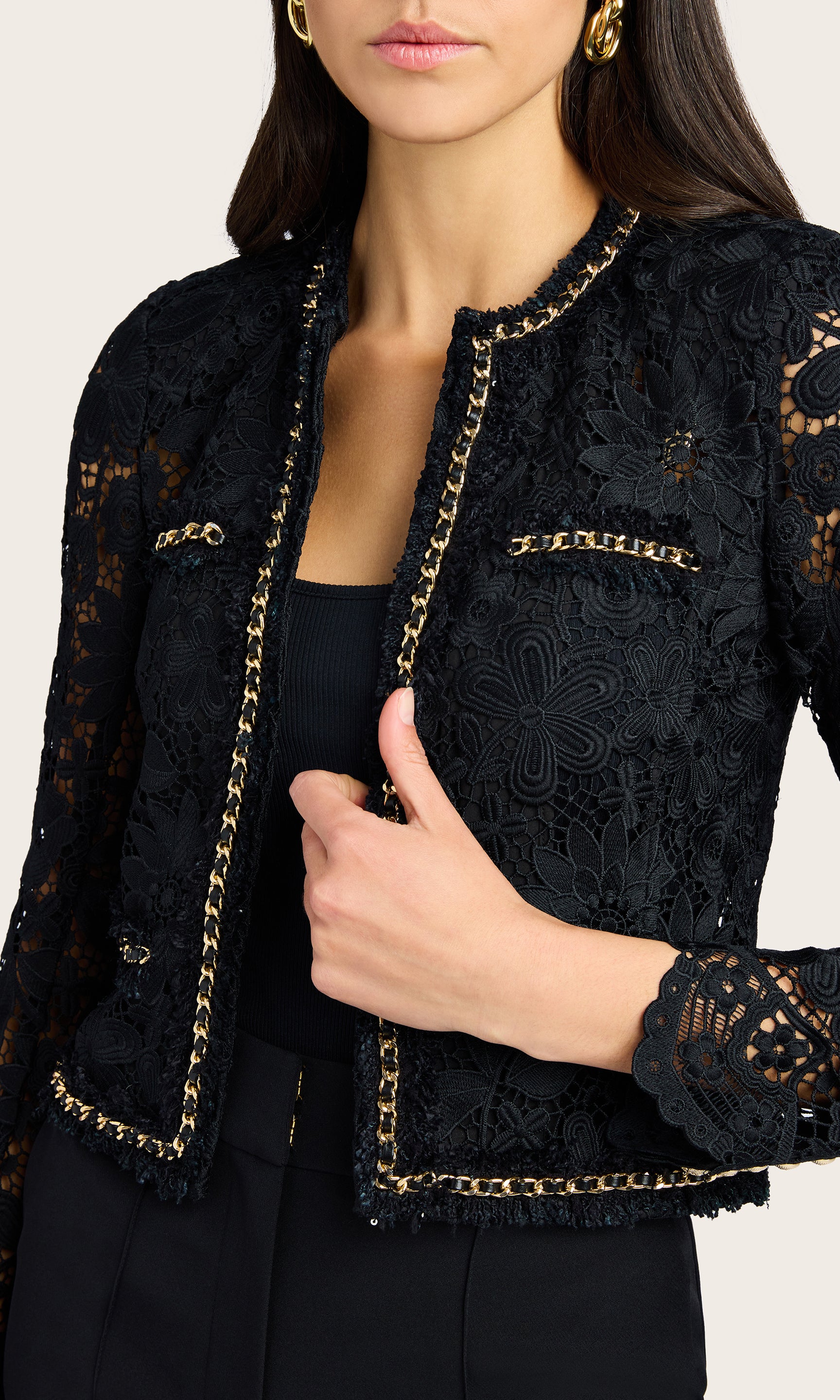 Close-up detail of the black lace jacket focusing on the lace texture and gold trim