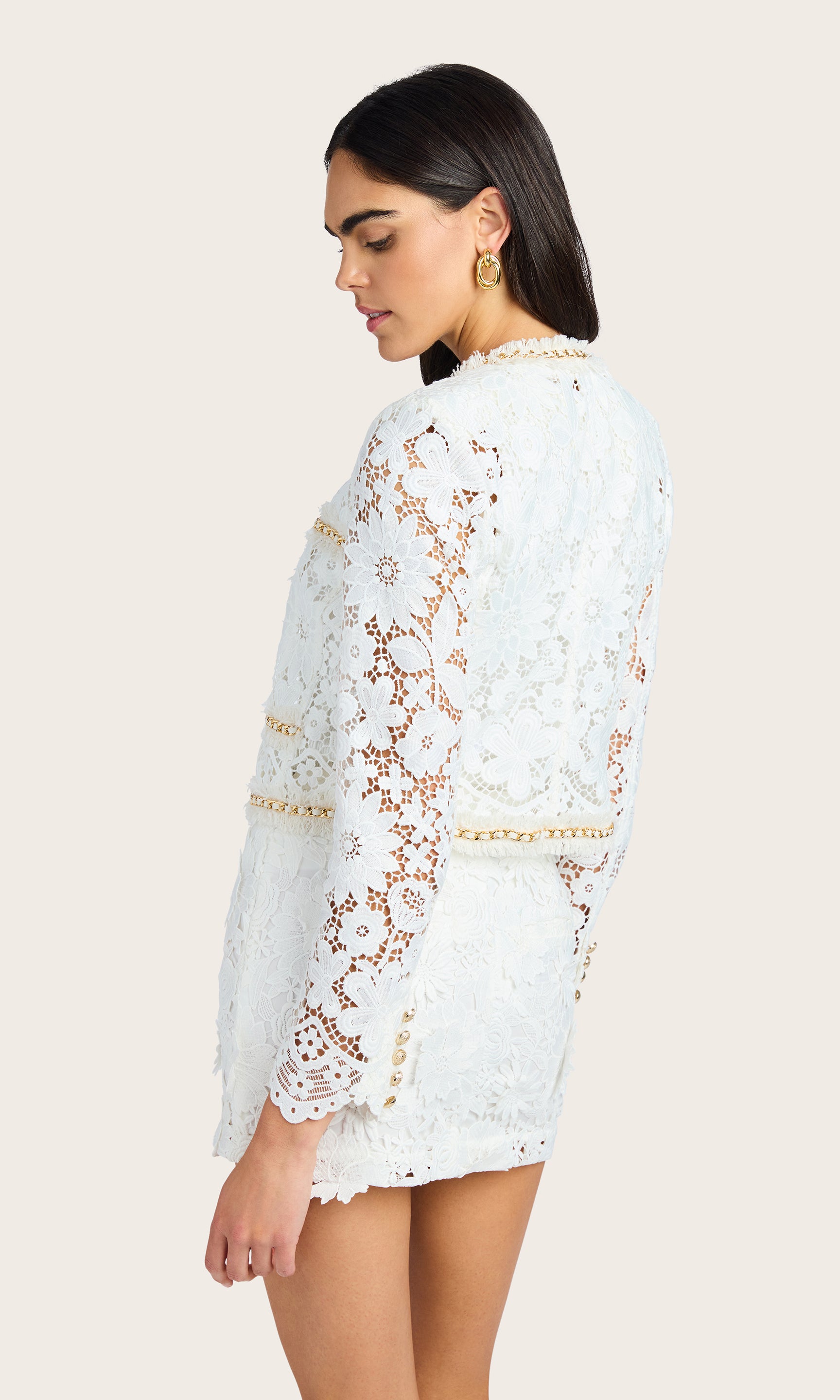 Side-facing studio view showing the silhouette and sleeve detail of the white lace blazer
