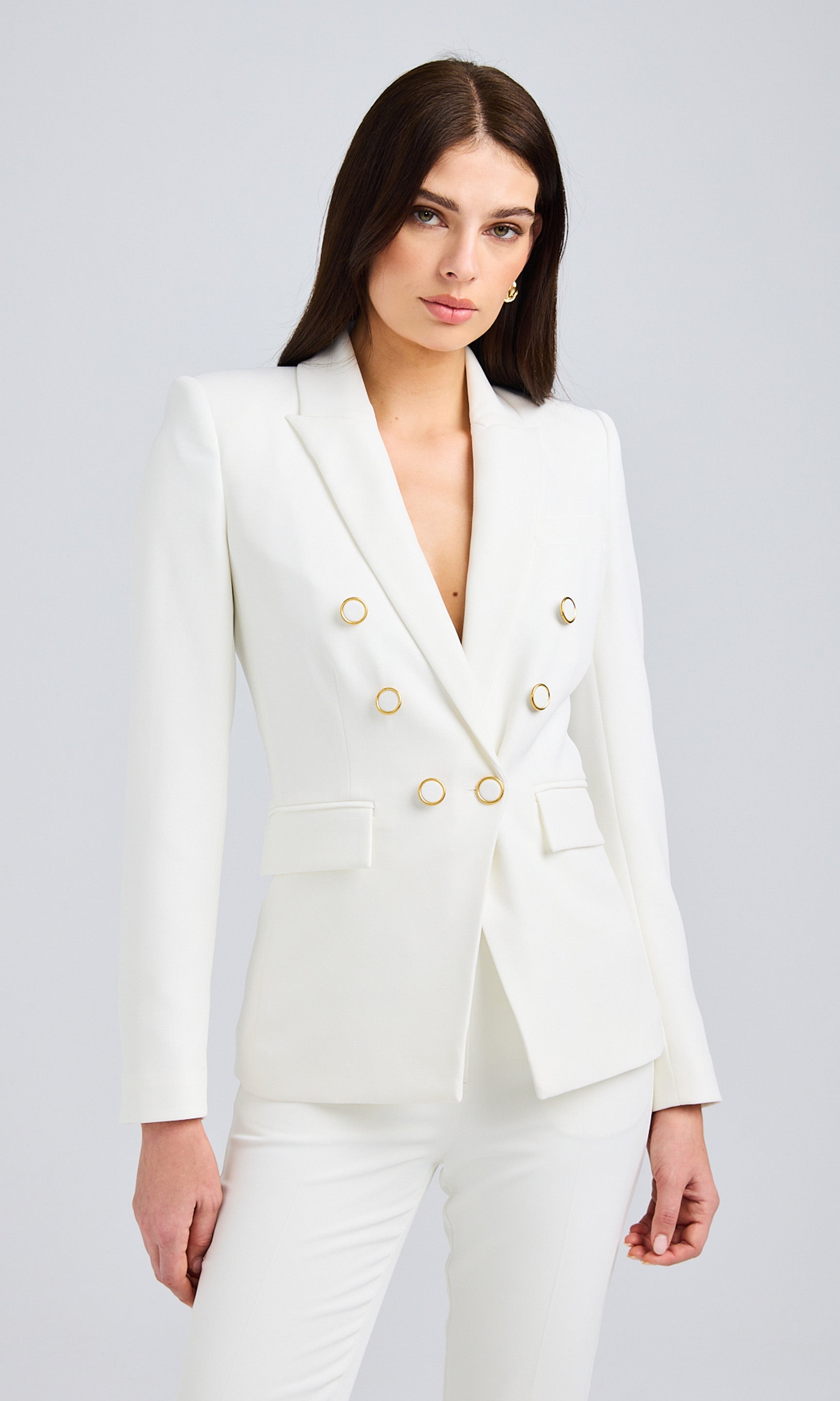 Front view of a model wearing a white double-breasted blazer with gold button details and tailored fit.