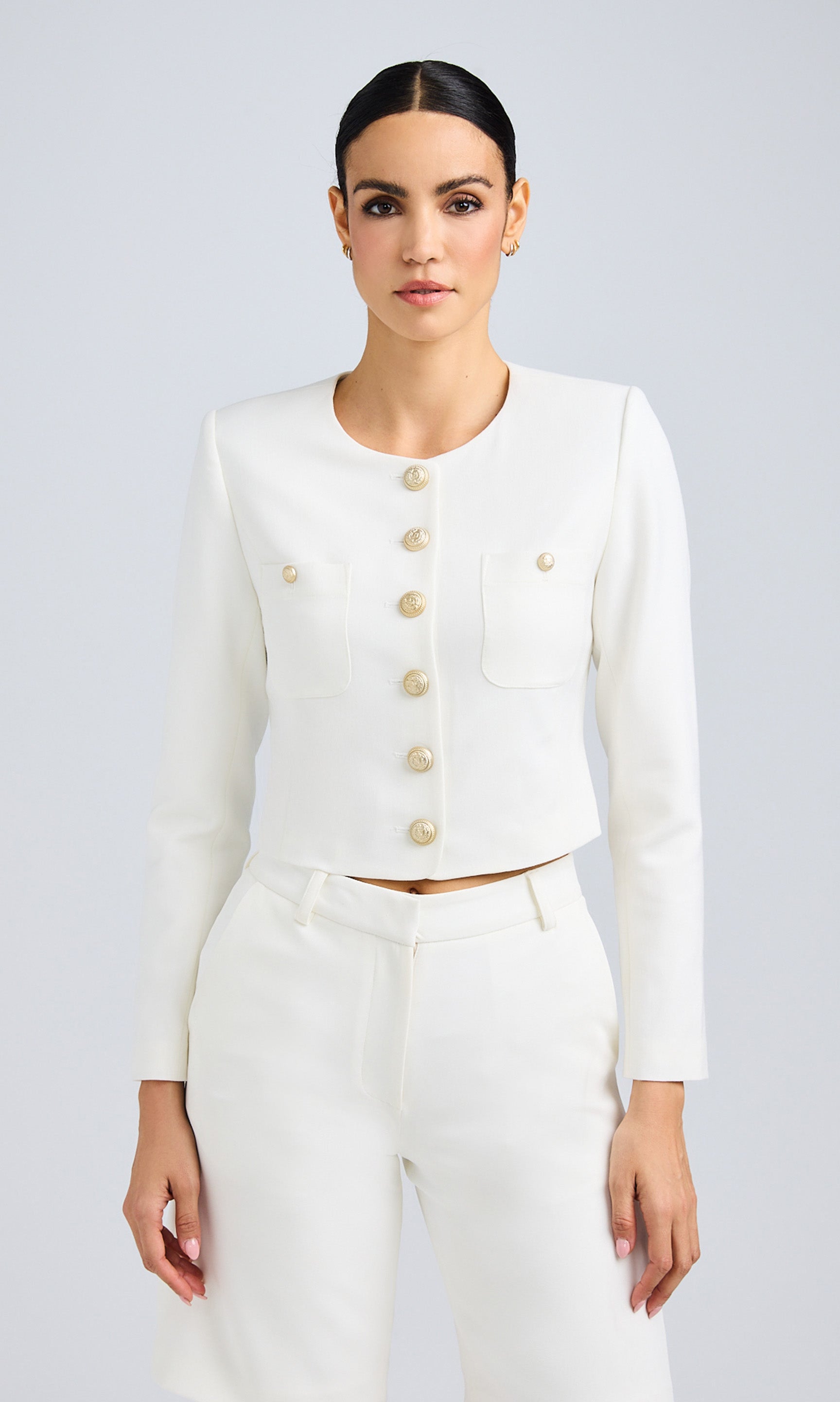 Front view of a model wearing a white structured jacket with gold buttons and matching shorts.