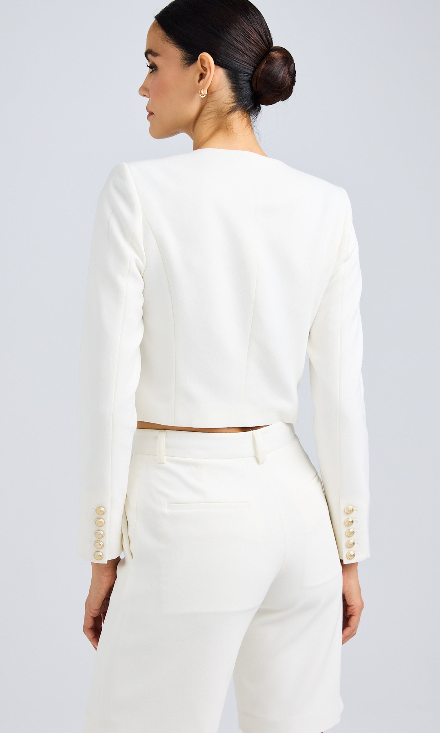 Back view of a model wearing a white structured jacket, highlighting the tailored fit.