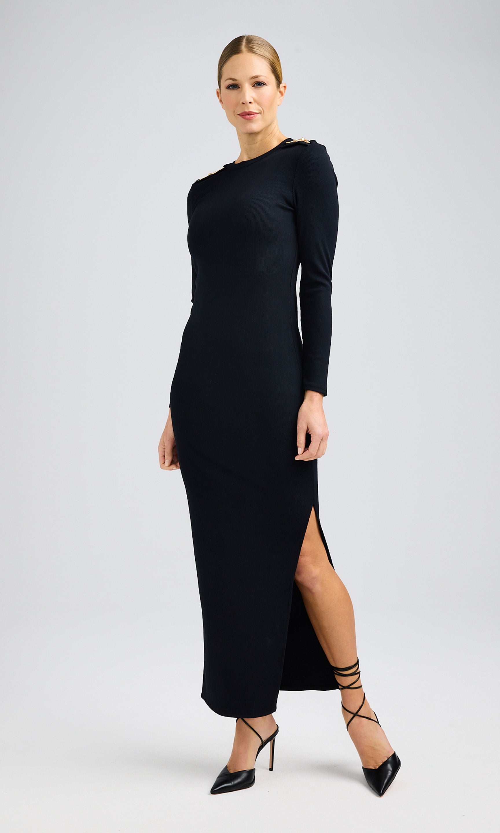Woman wearing a black, long-sleeve maxi dress with a side slit and black heels