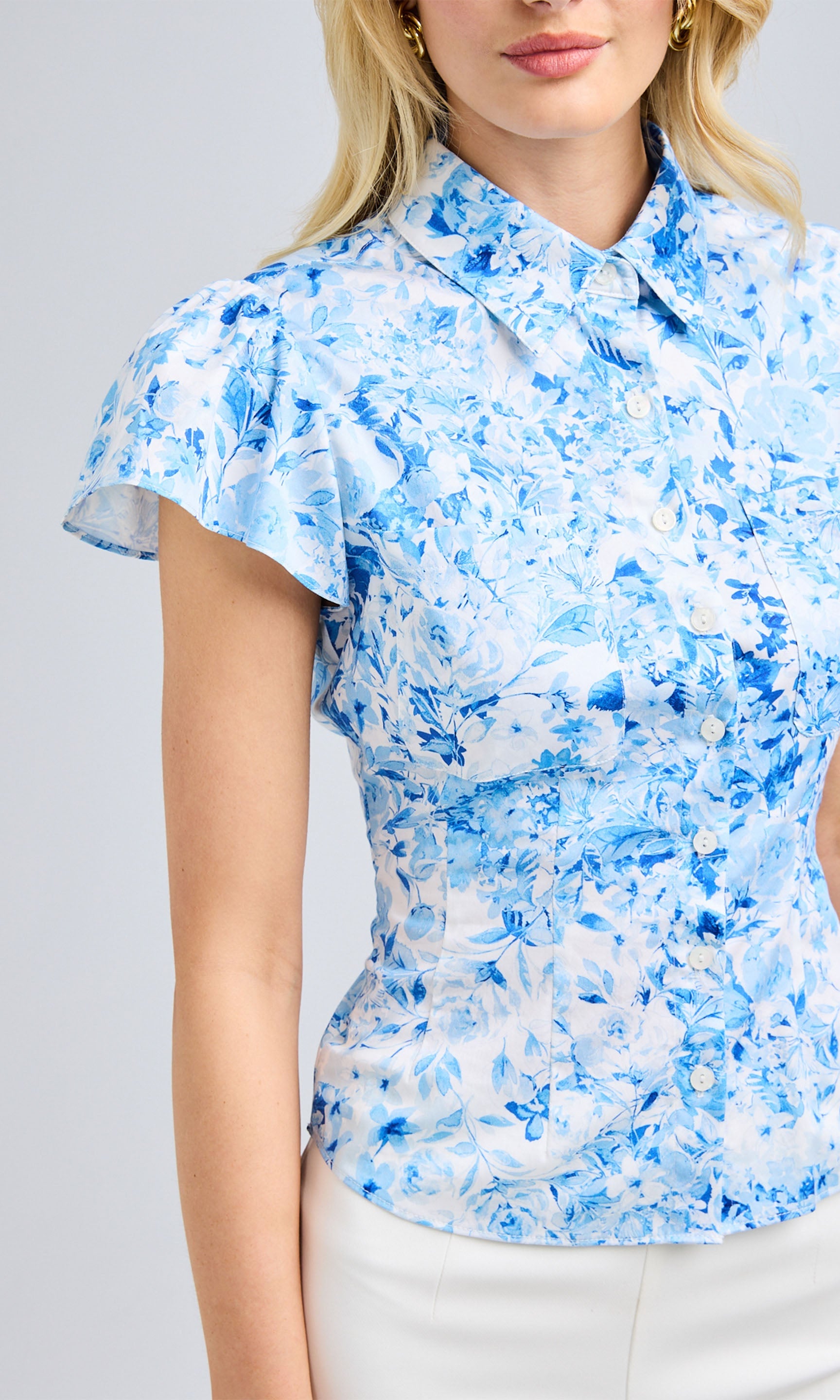 Close-up of the blouse, highlighting the structured collar, delicate flutter sleeves, and intricate floral pattern.