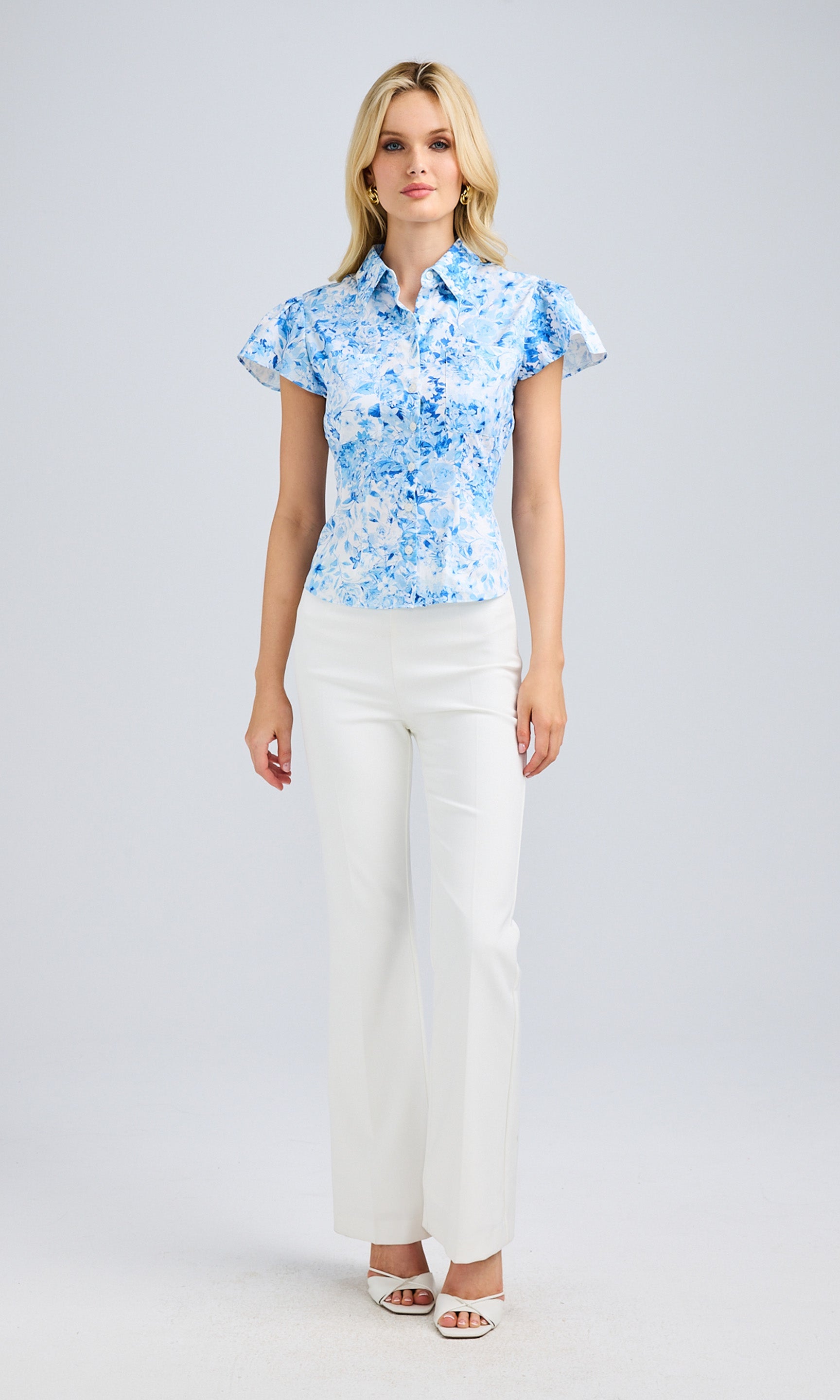Full-body view of the model in the blouse and white pants, emphasizing the elegant styling and polished look.
