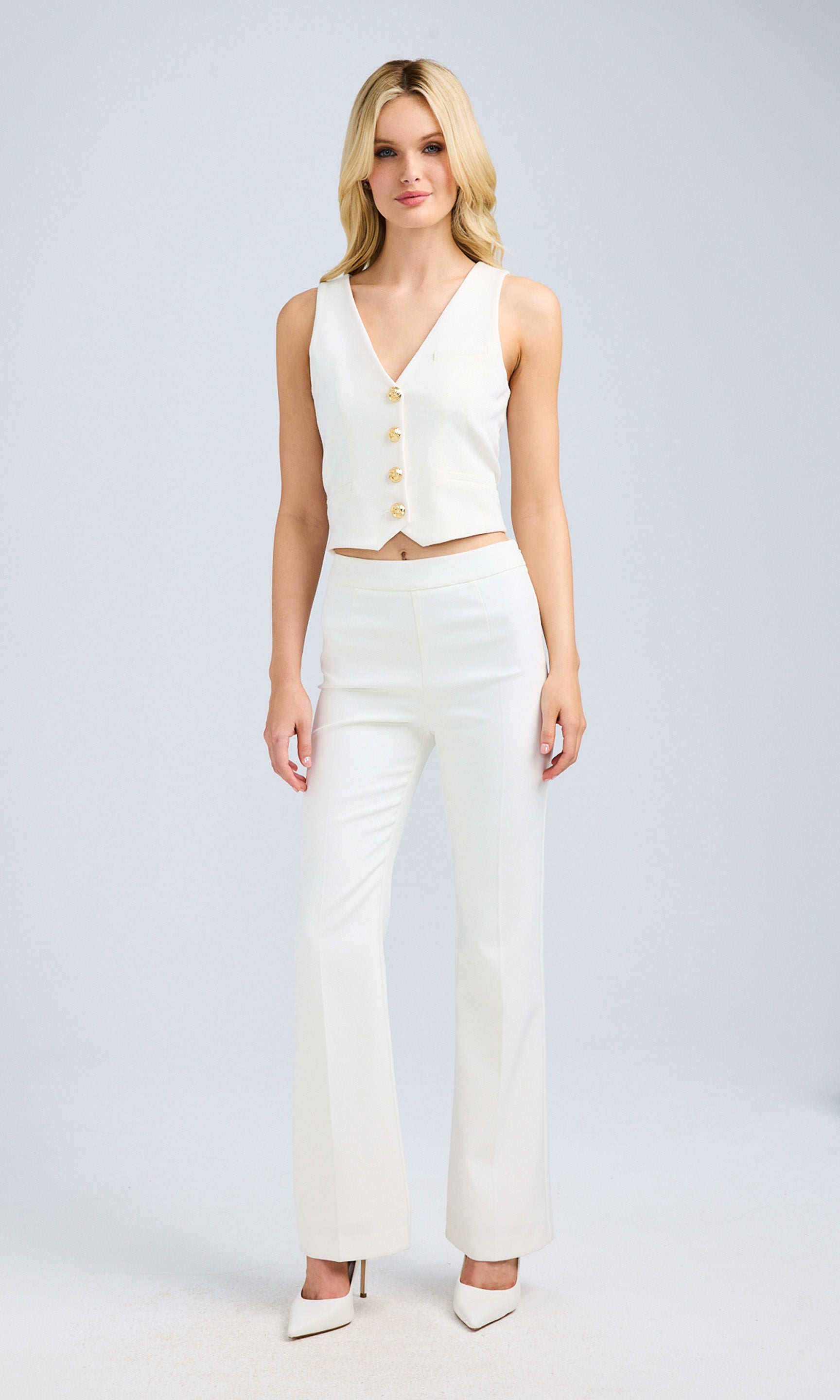Full-body shot of a model wearing the white vest and coordinating pants, styled with heels.