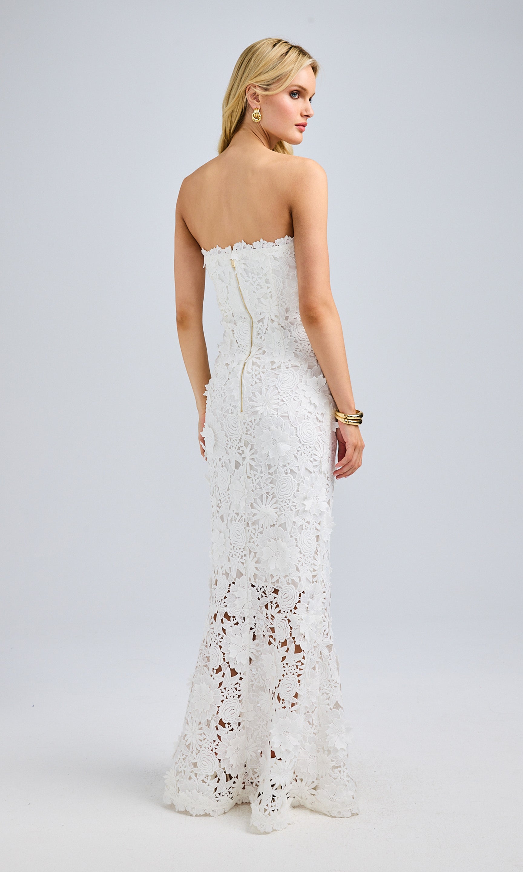 Rear view of the model in the lace gown, highlighting the fitted bodice and scalloped lace trim at the hem.