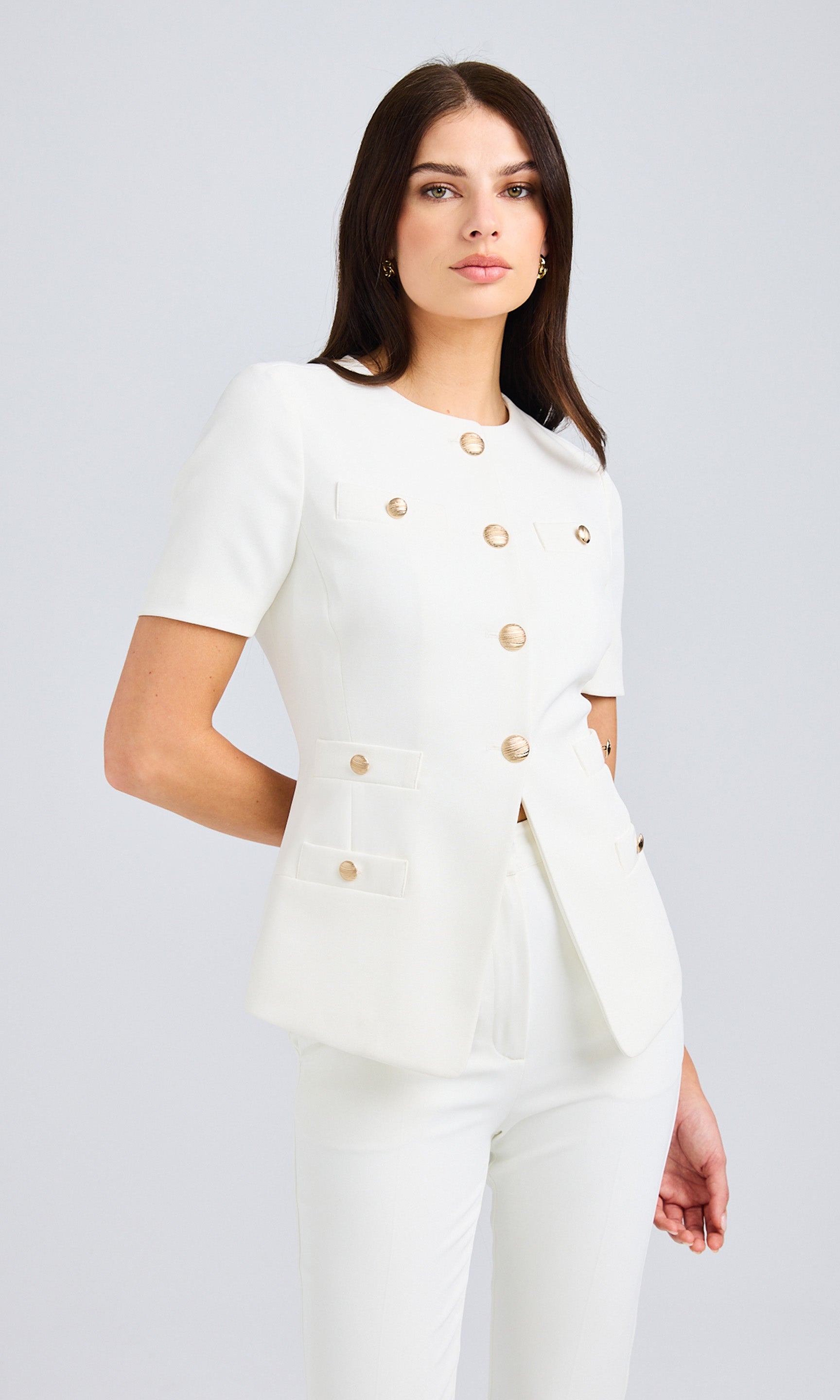 Side view of the white top, emphasizing the structured cut and gold button details.