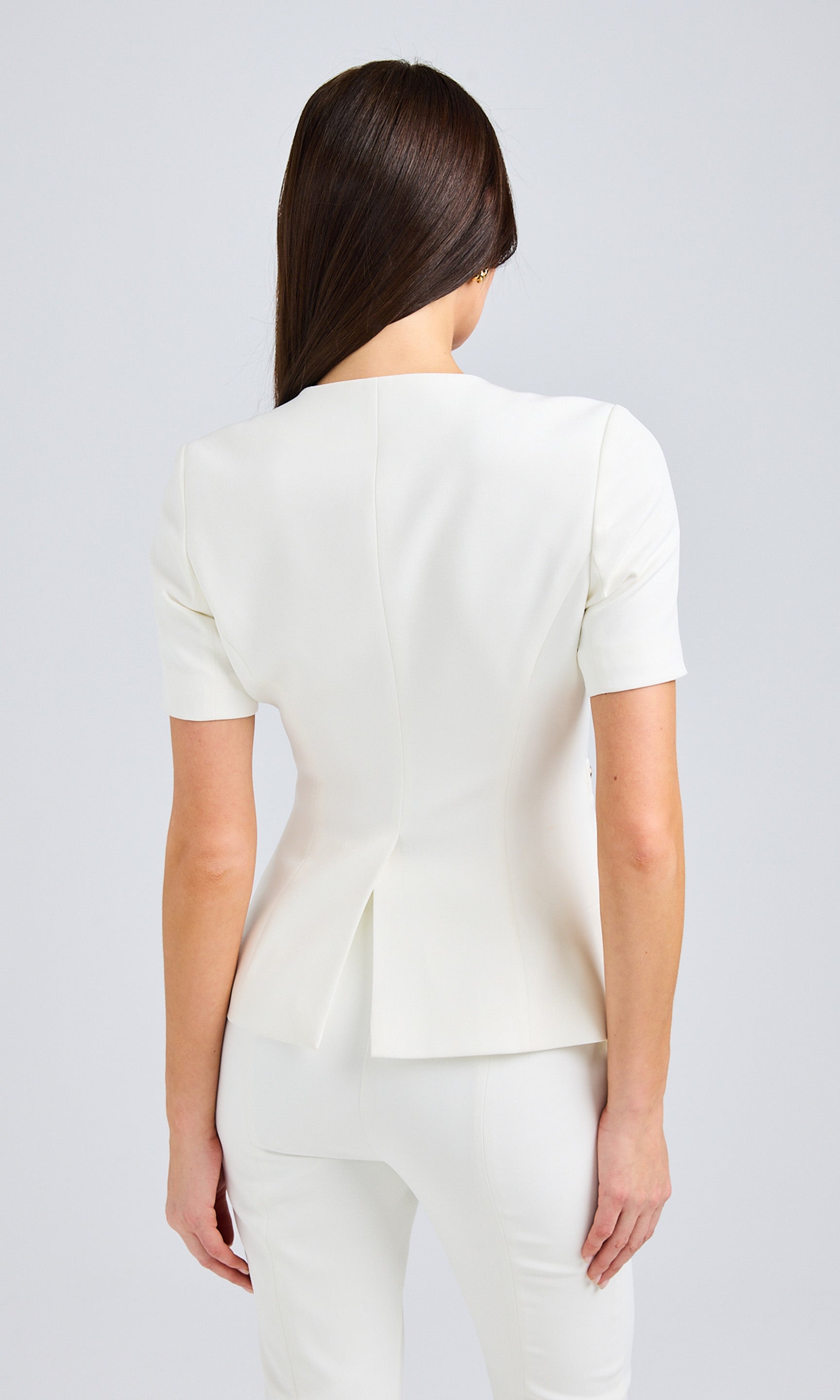 Back view of the white top, showcasing its tailored silhouette.