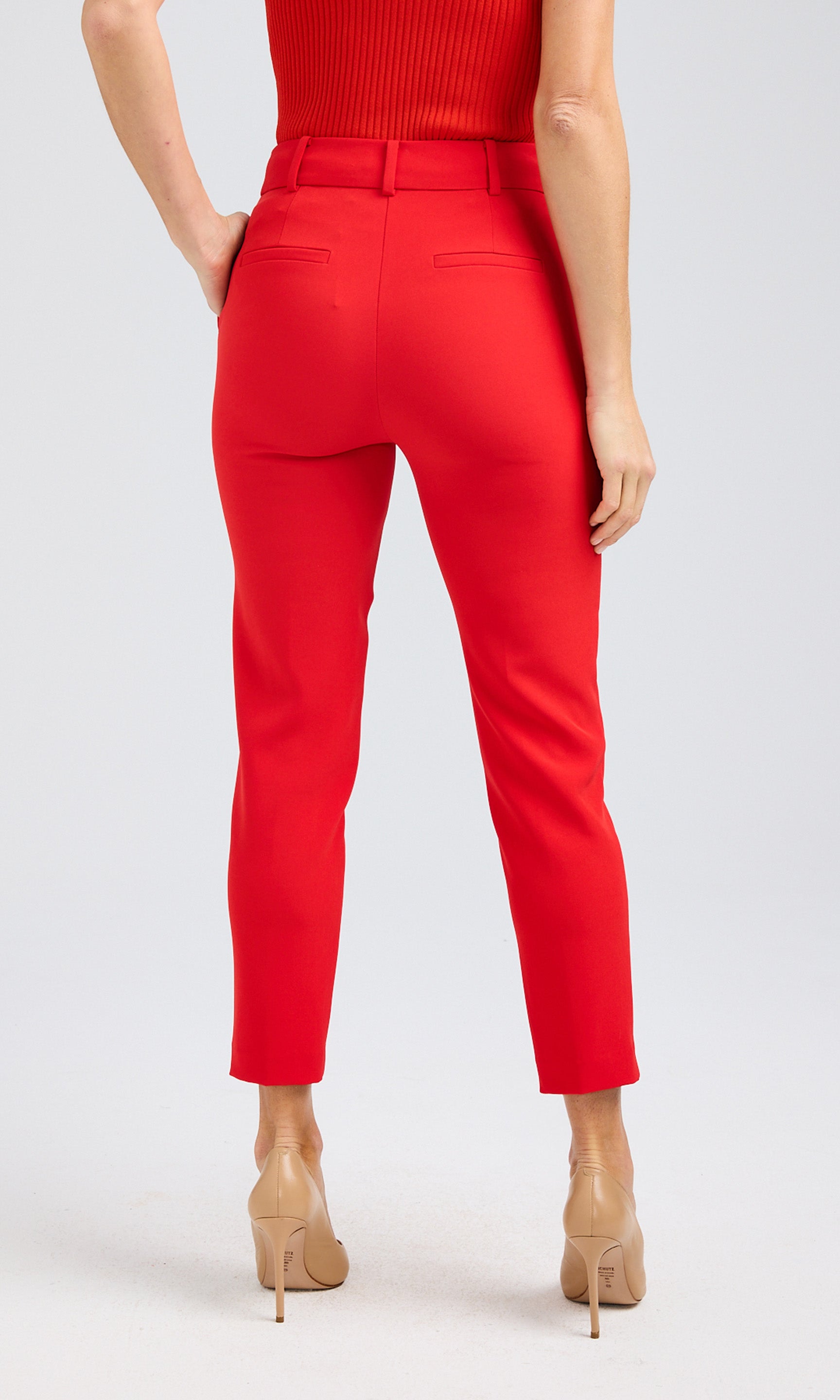 Rear view of red crepe pants with a tailored fit, paired with a red ribbed tank and nude heels.