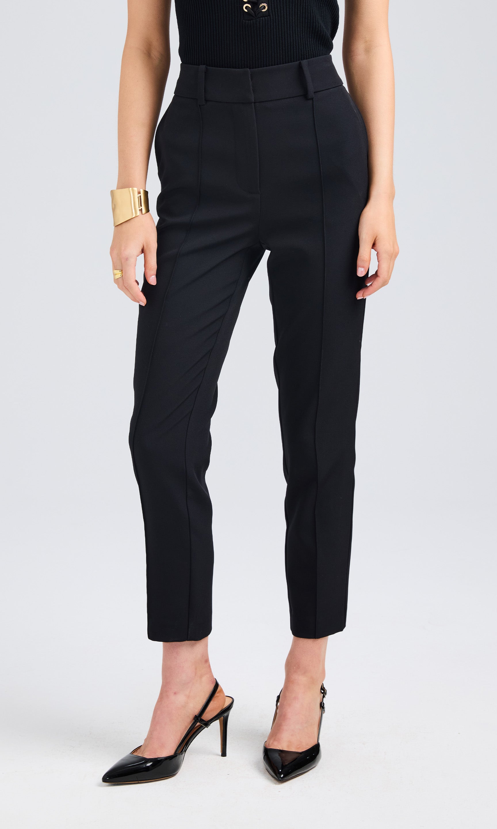 Front view of black slim-fit pants styled with pointed heels, showcasing a clean and tailored design.