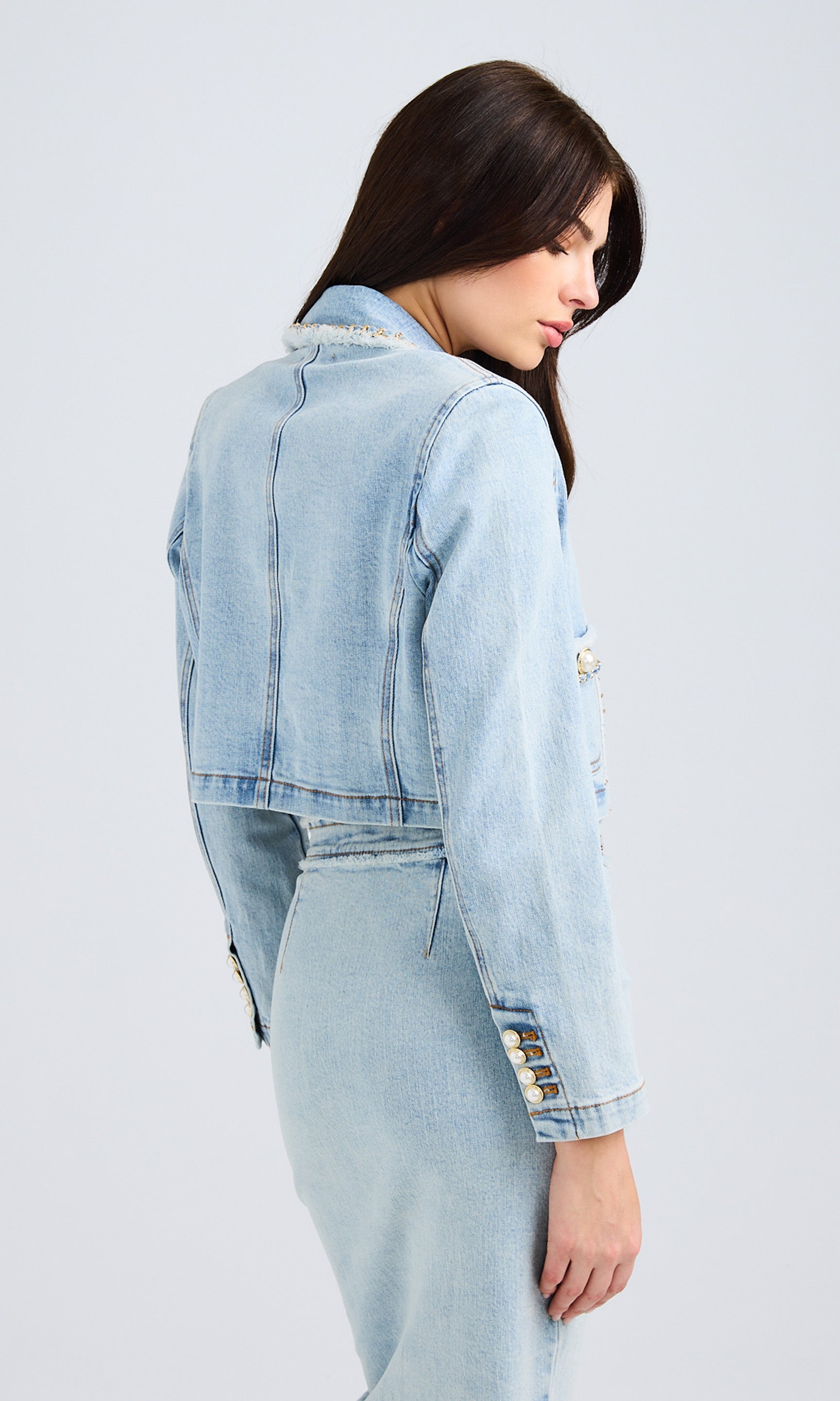 Side view of a model wearing a light-wash denim jacket, highlighting the sleeve detailing.
