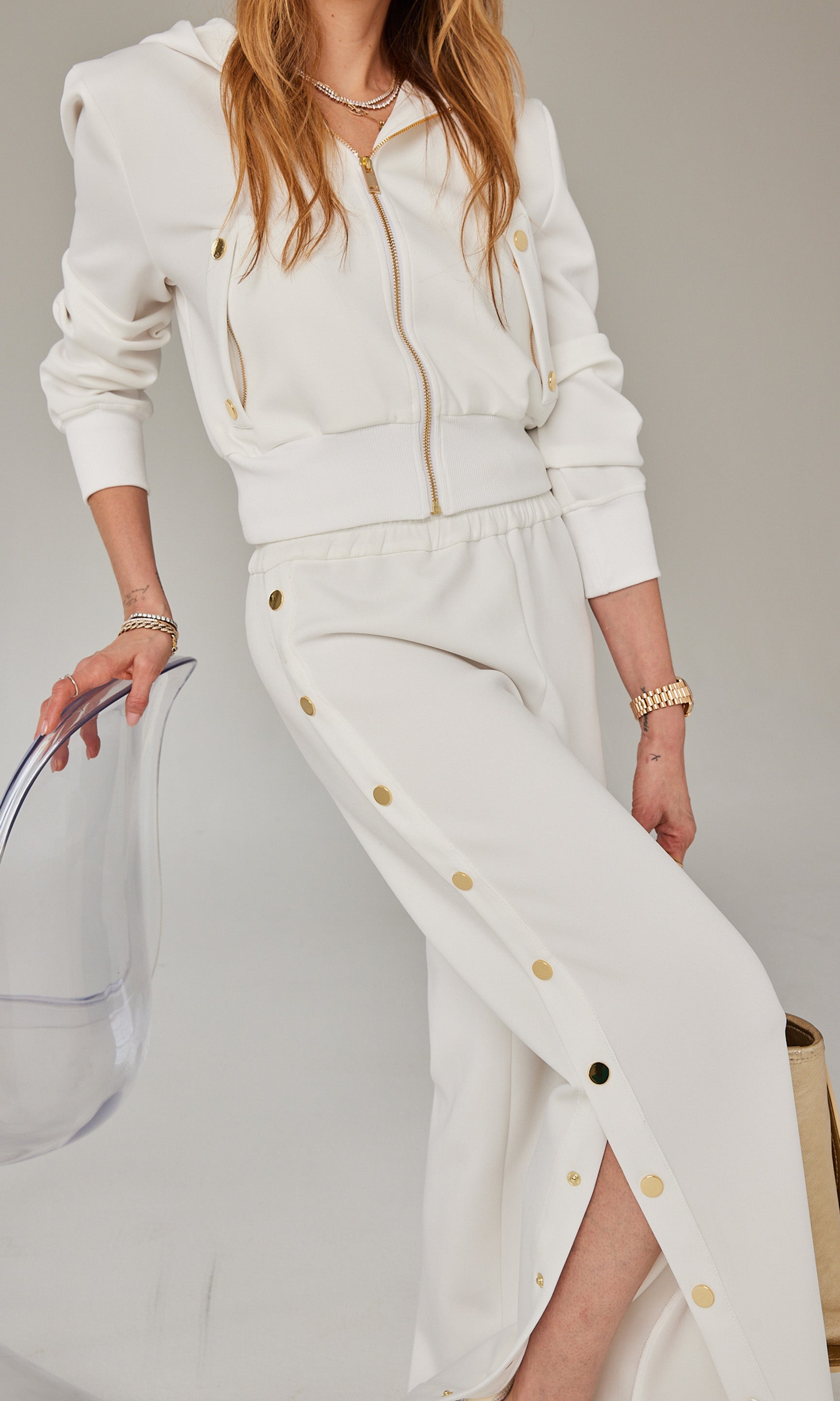 Close-up view of Roni in a white zip-up hoodie and matching snap-button pants, paired with embellished Chanel sneakers.