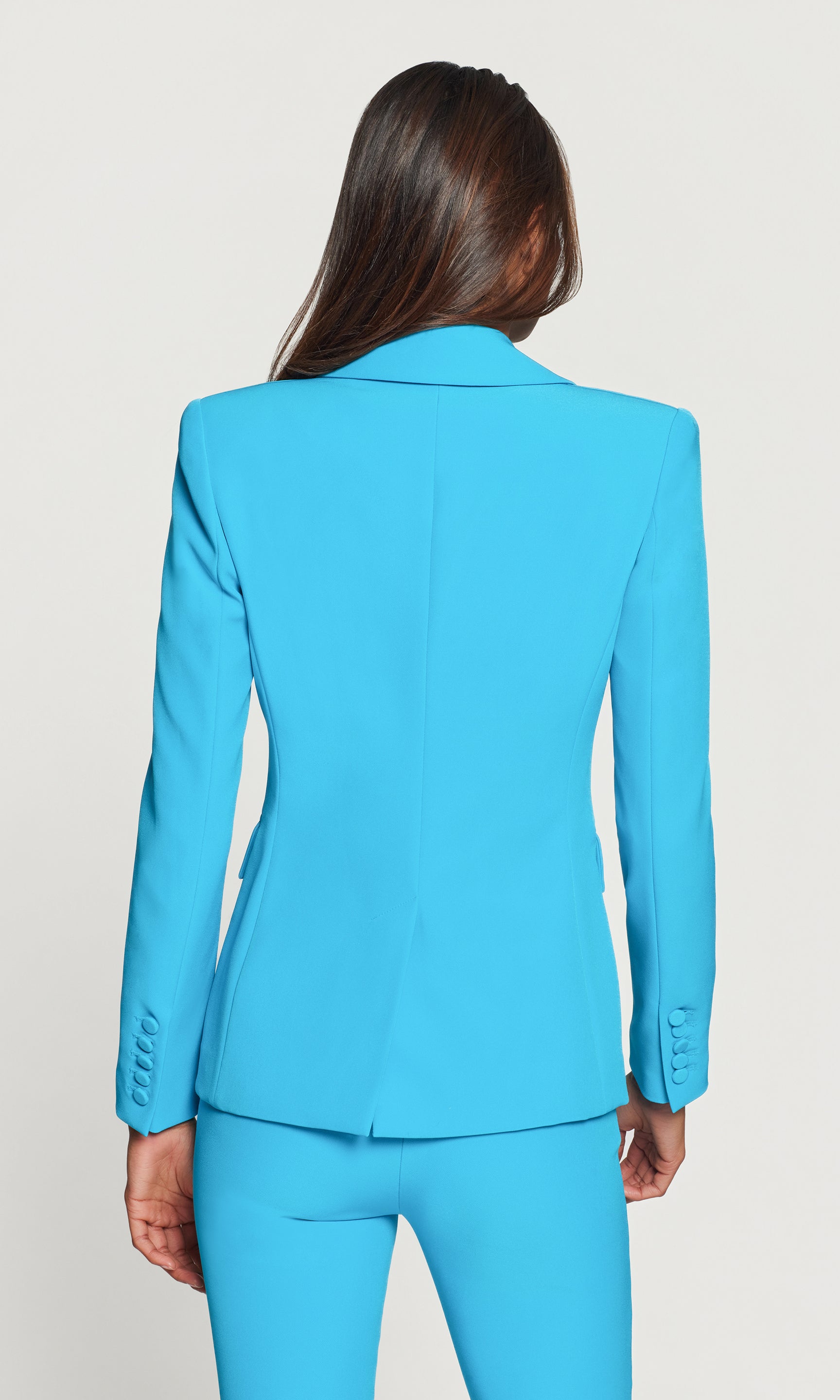 Back view of person wearing a bright blue suit on a plain background