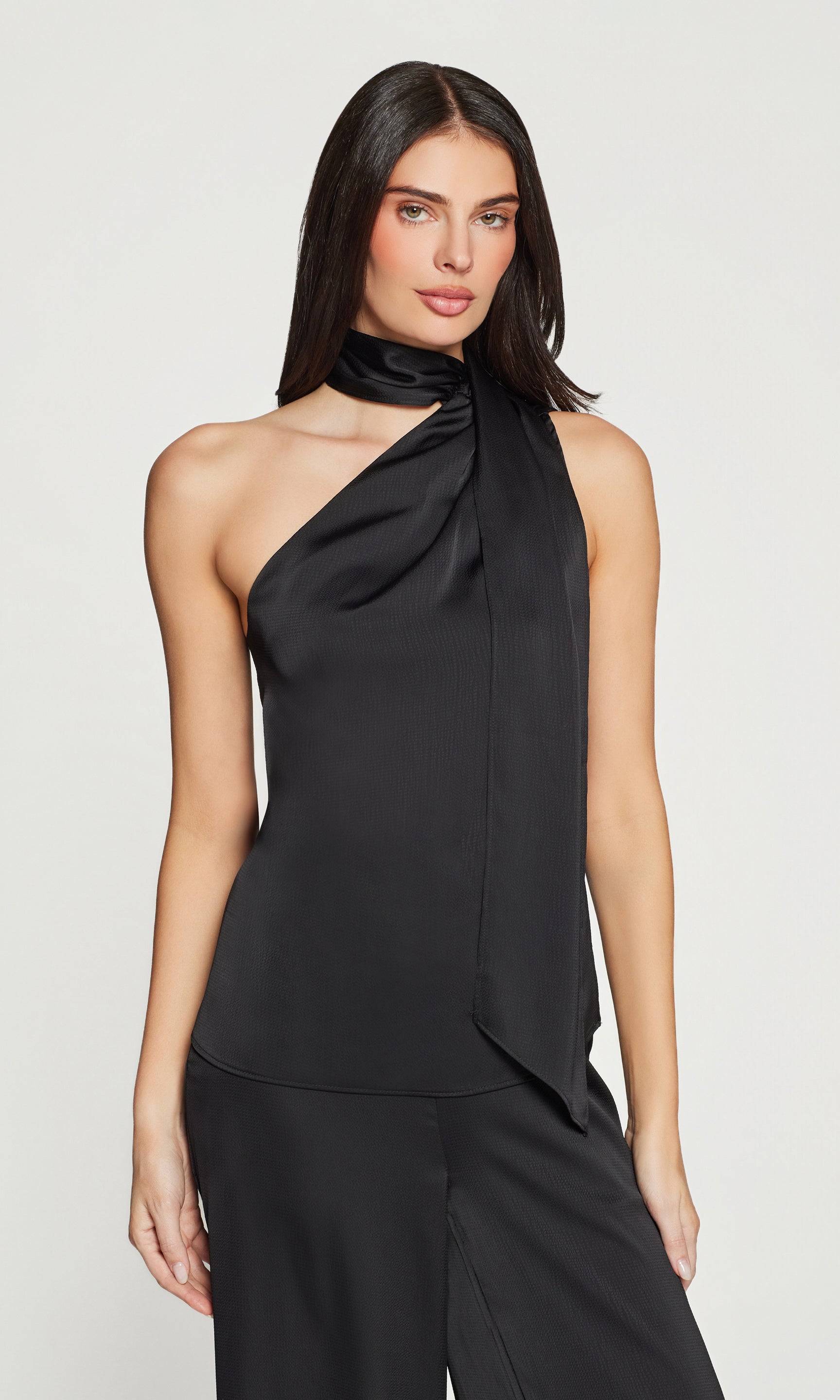 Woman wearing a black halter neck top and black pants on a white background