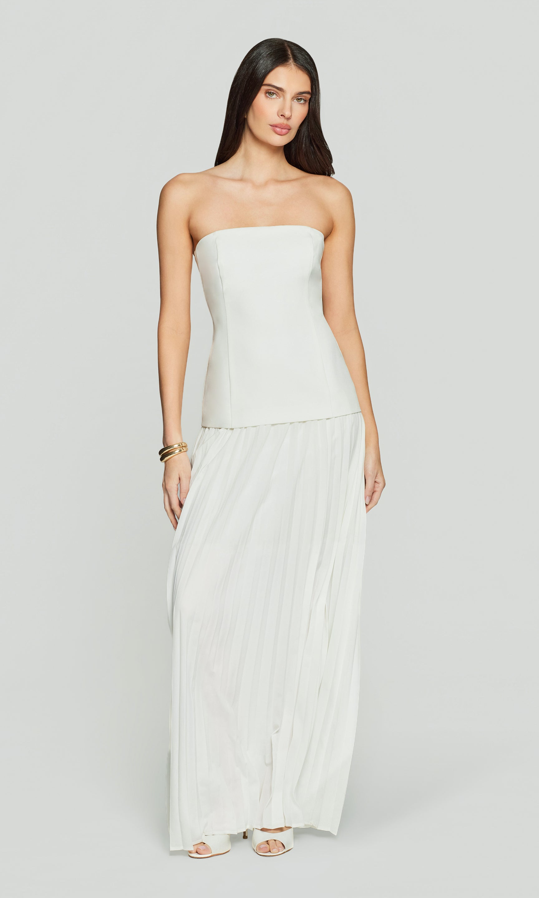 Woman wearing a strapless white dress on a plain background