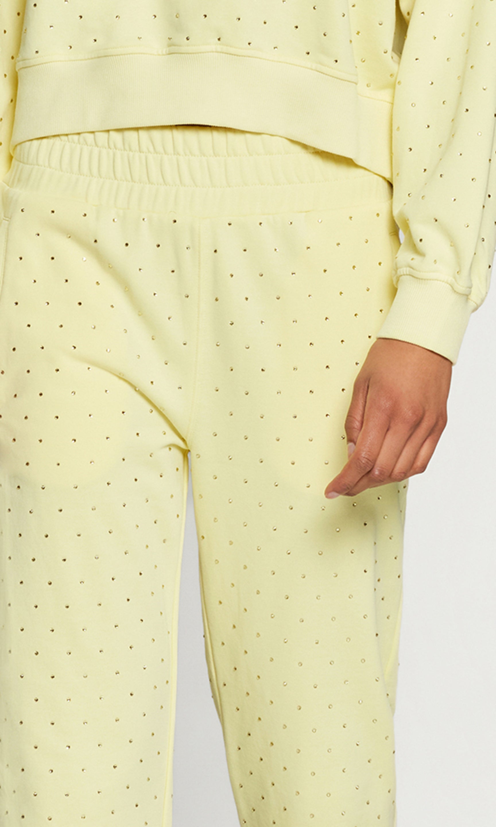 Close-up of light yellow pants worn by a person on a white background