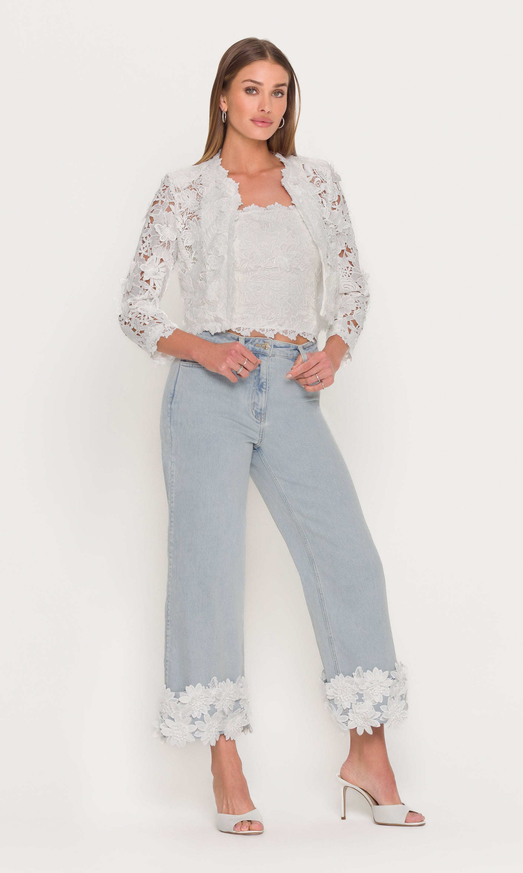 In a full body front view, the model wears the Paloma Lace Combo Jeans in light wash denim, highlighting the wide-leg shape and lace cuffs styled with a lace top.