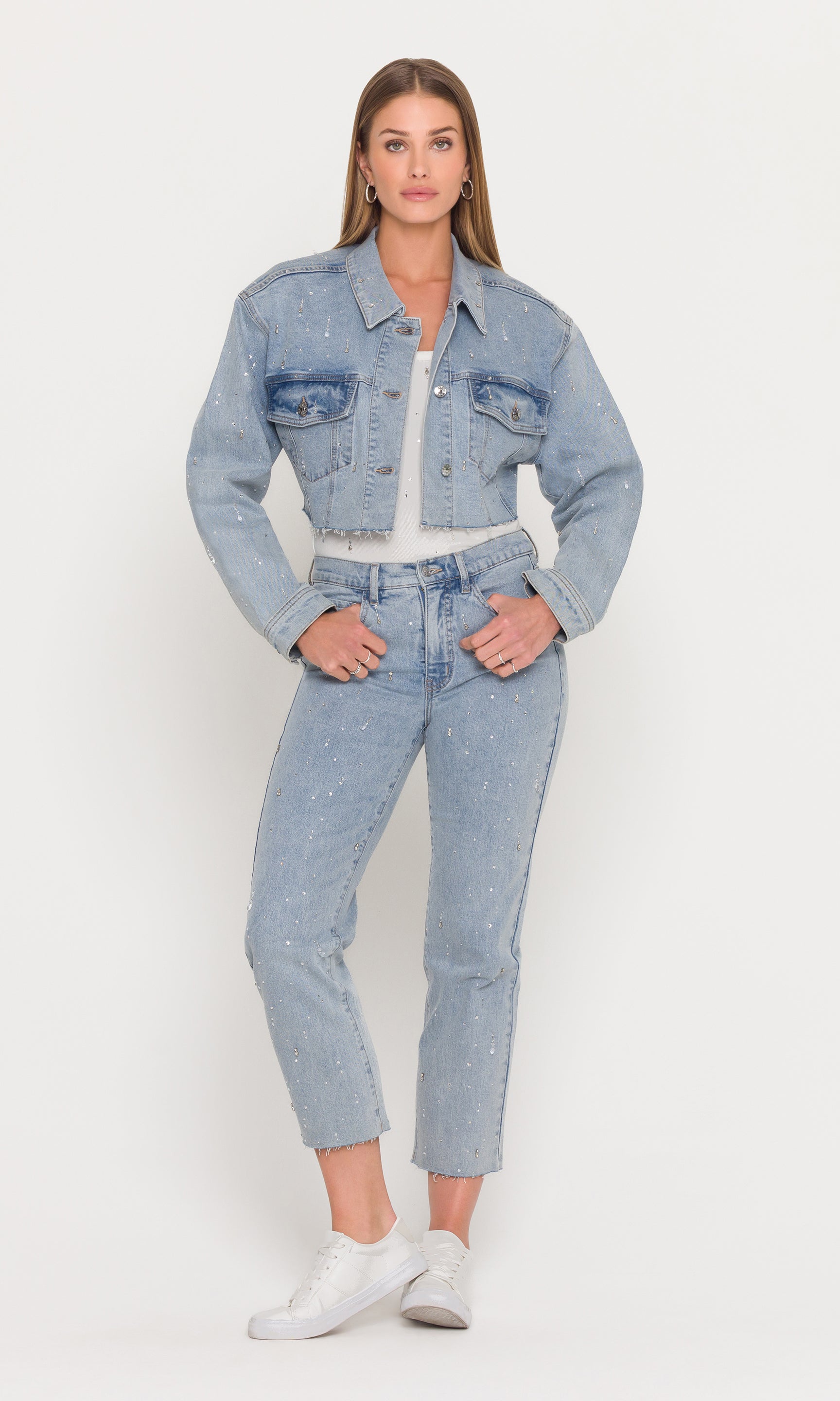 Woman wearing a light blue denim jacket and jeans on a white background