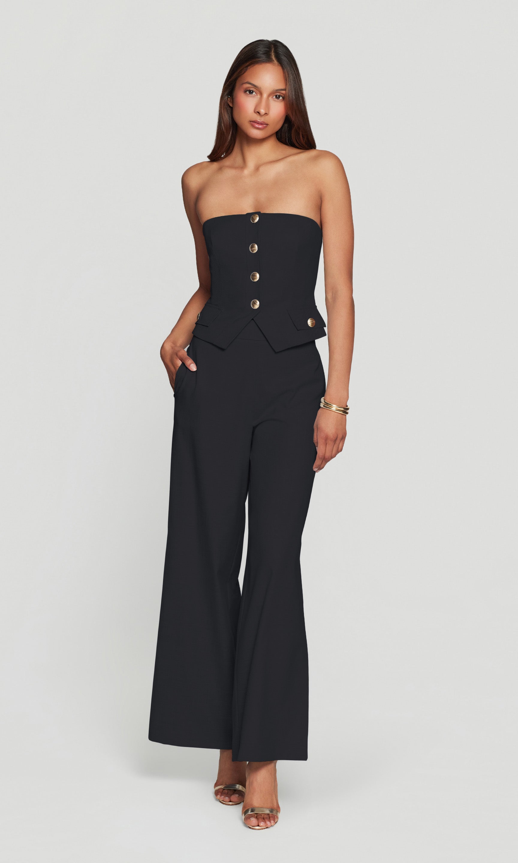 Woman wearing a black strapless top & wide-leg pants on a white background