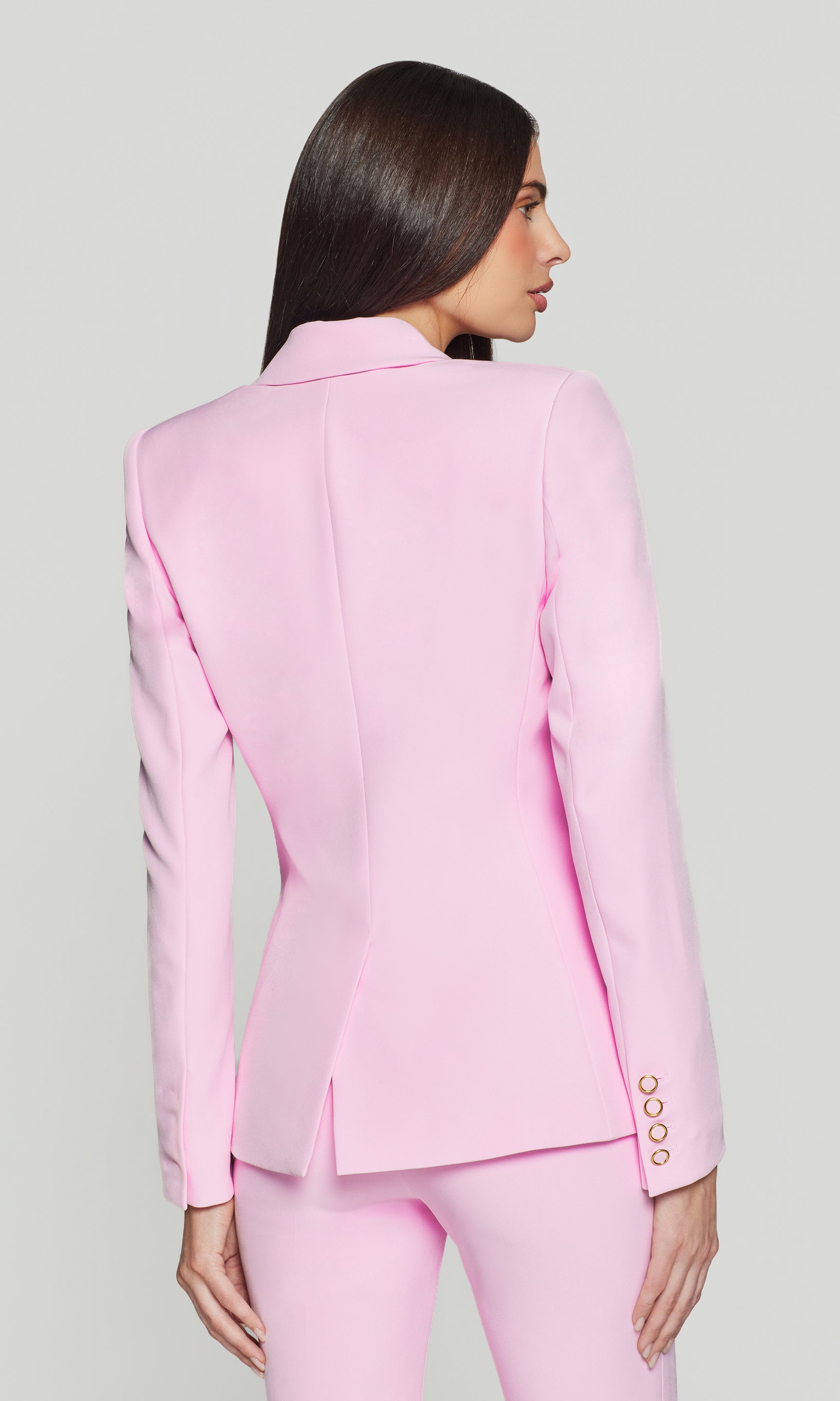 Back view of woman wearing a pink suit with a plain background
