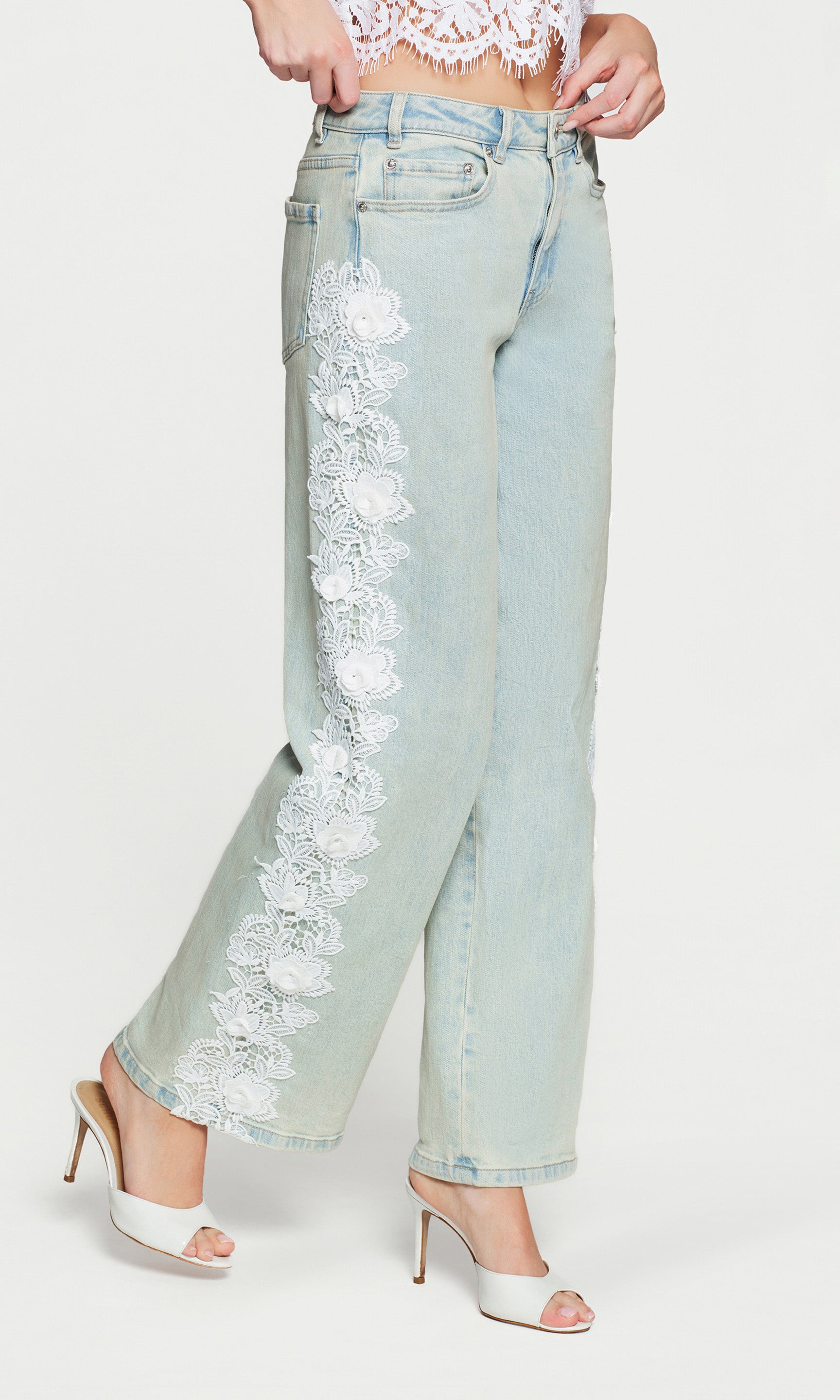Side view of light blue jeans with floral embroidery on a white background