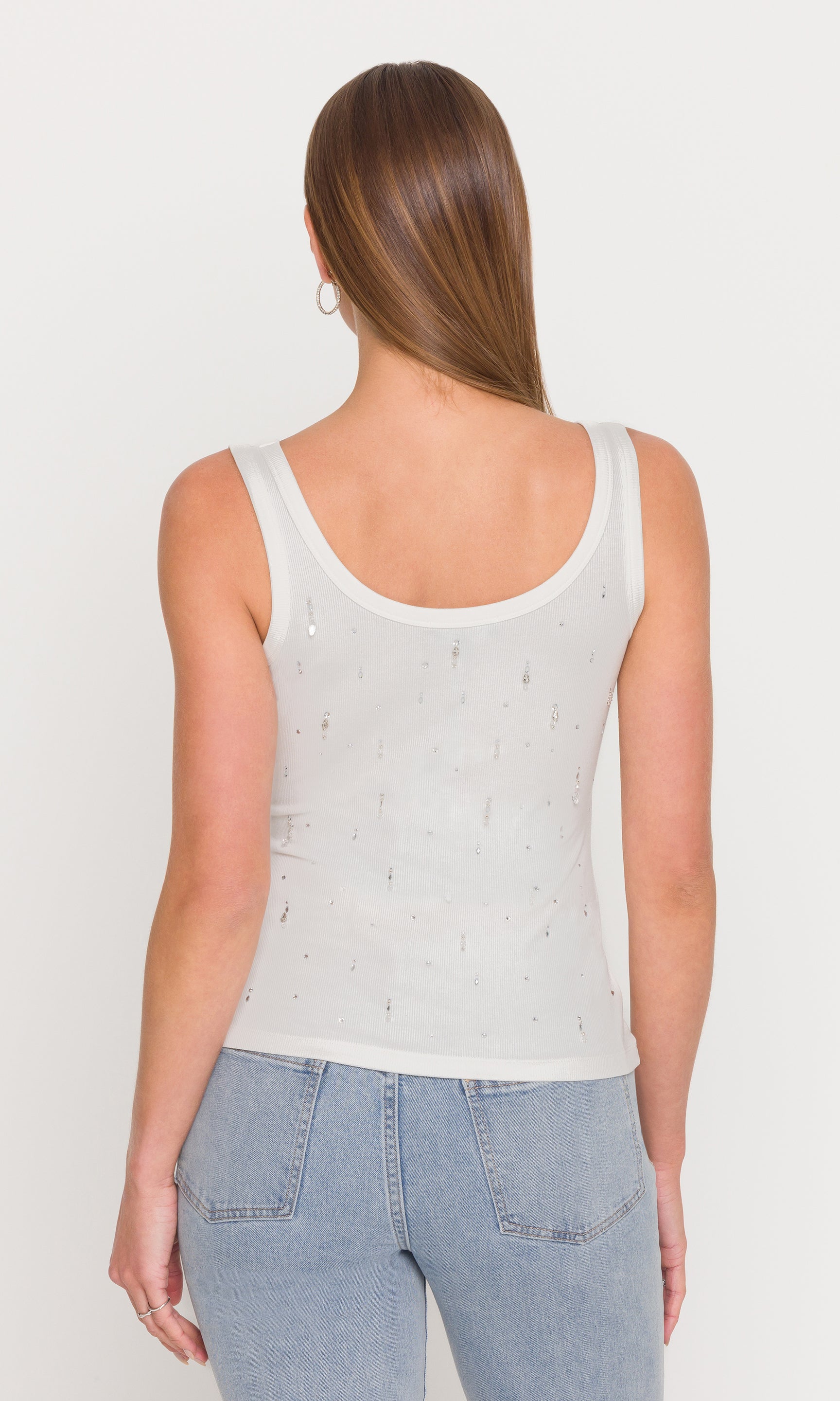 In a rear view, the model wears the Evita Embellished Top in white, showing the smooth back and streamlined tank cut.