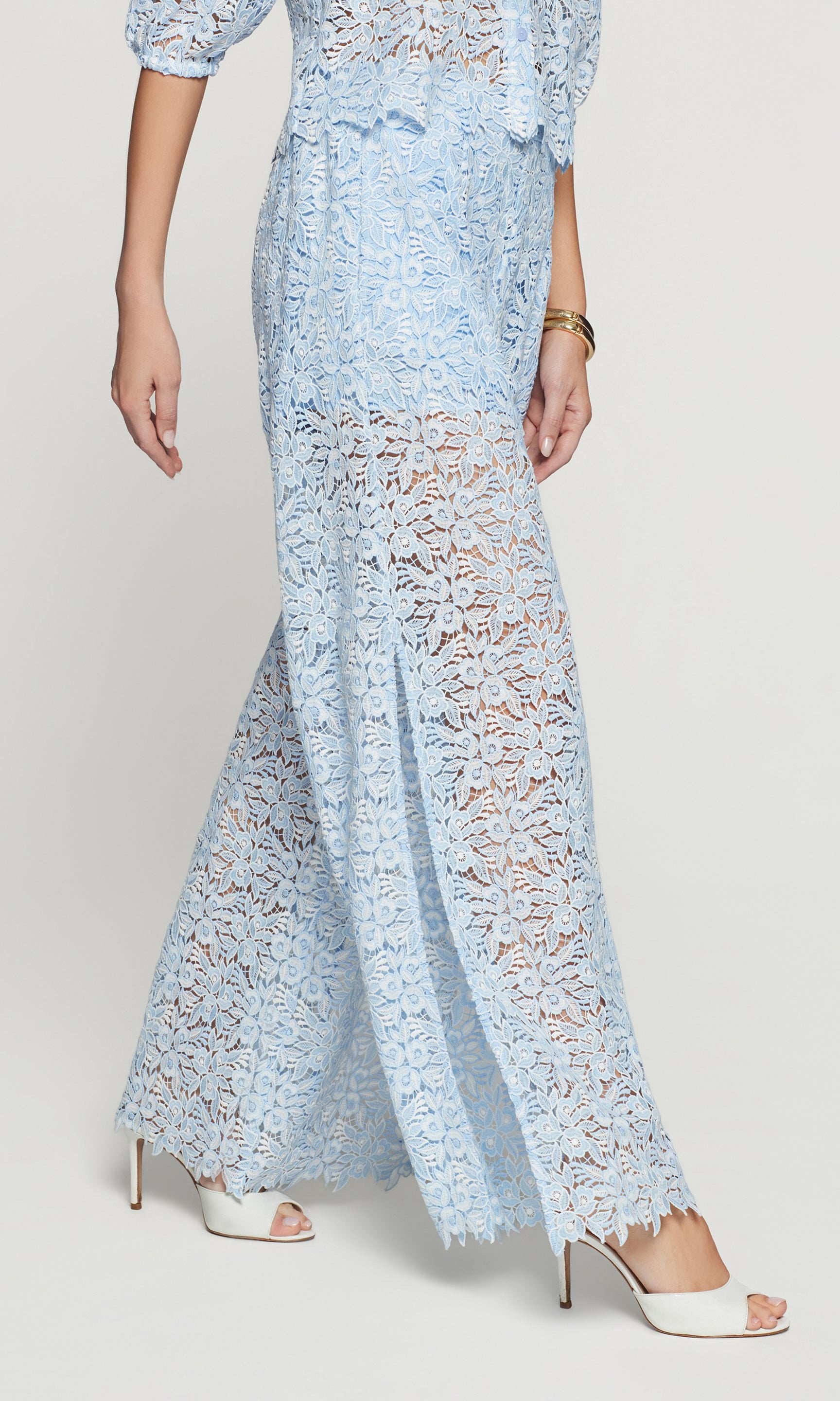 Side view of light blue lace pants with a high slit worn by a person on a white background