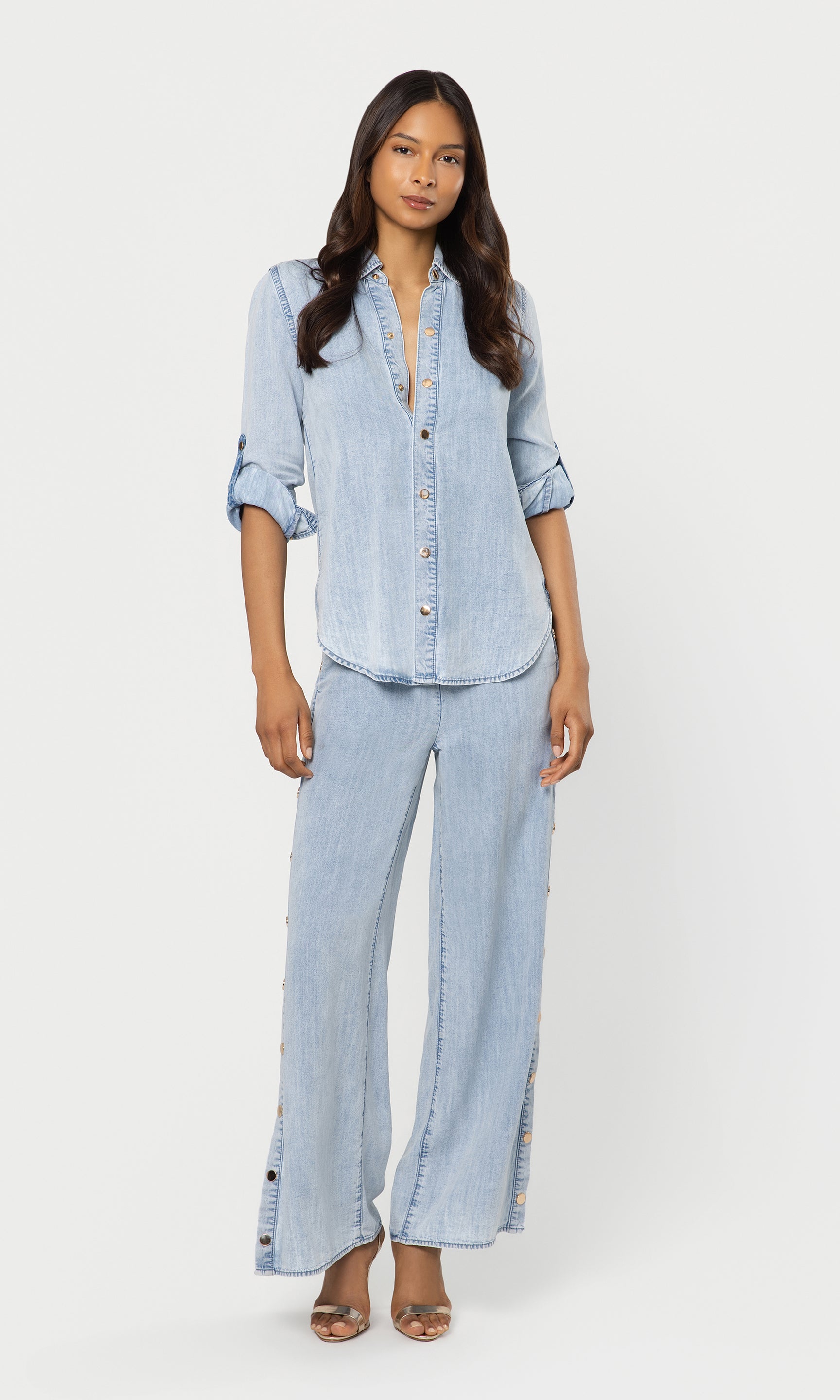 Woman wearing a light blue denim outfit on a white background