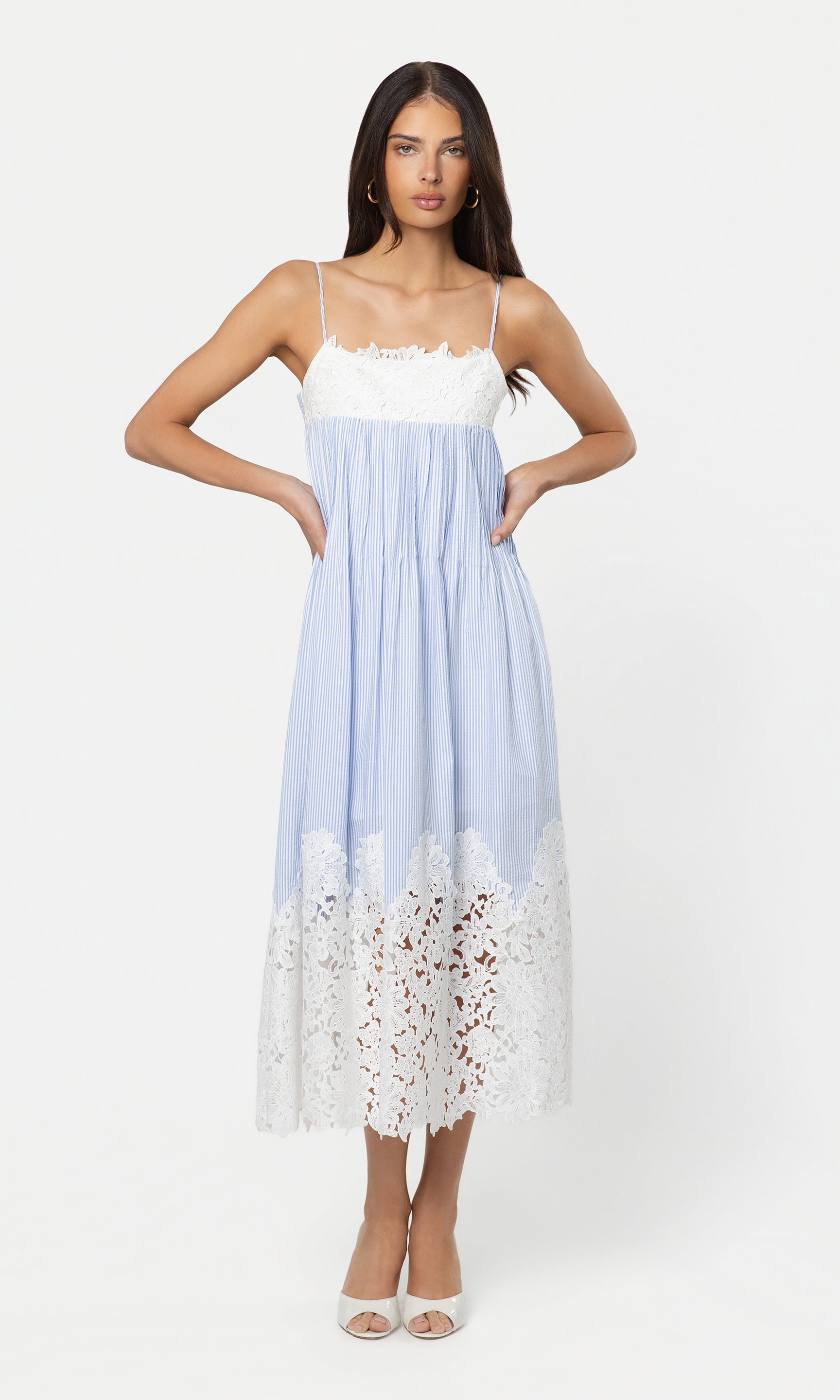 Woman wearing a light blue dress with white lace details on a white background