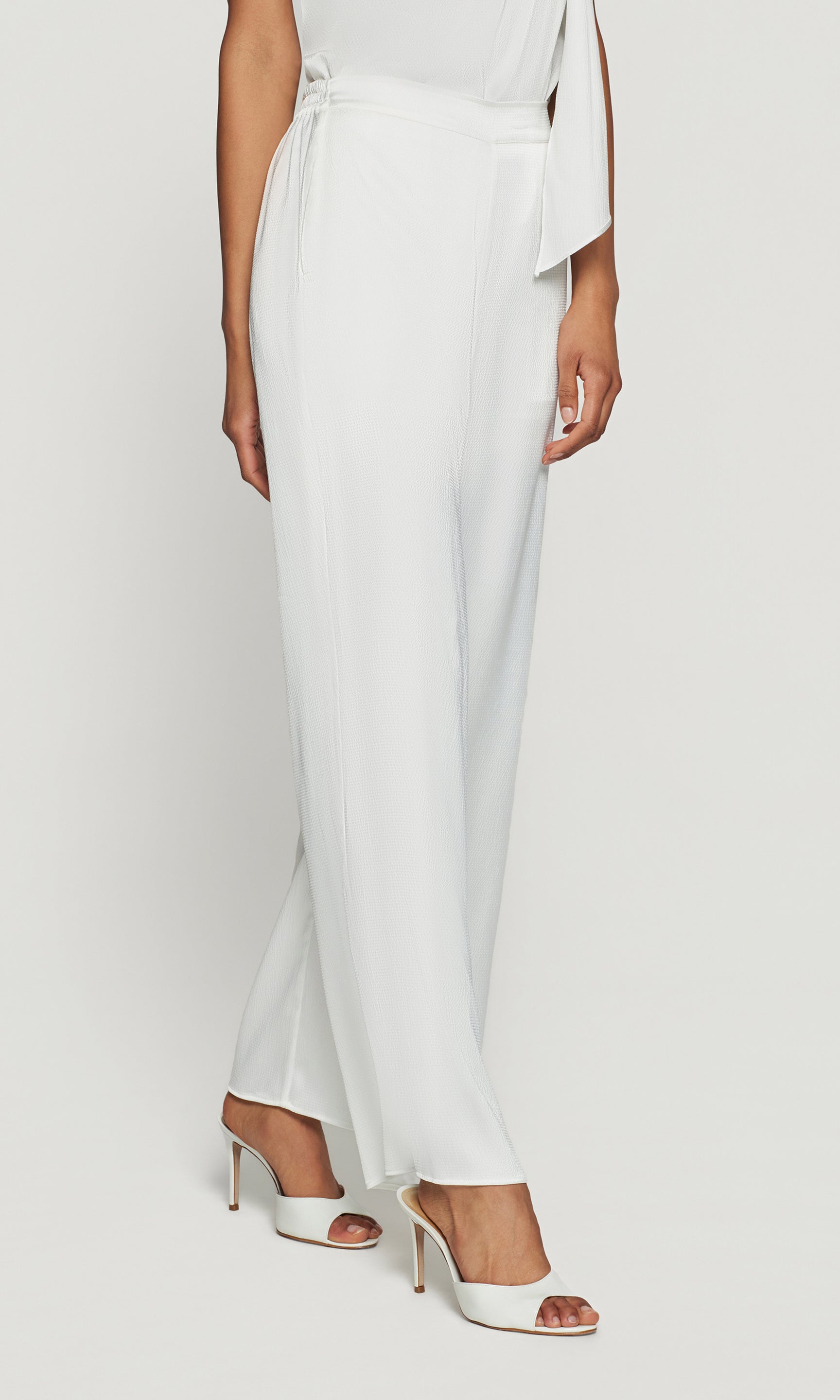 White outfit with a draped top and wide-leg pants on a white background