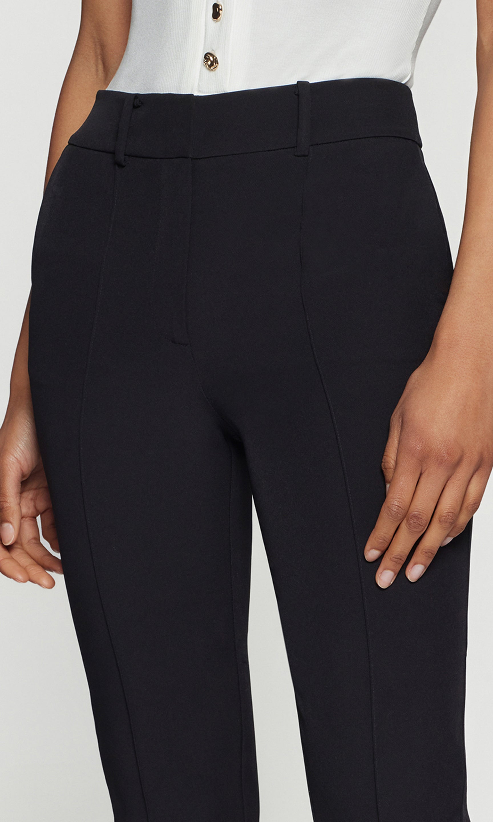 Close up of black pants worn by a person on a white background