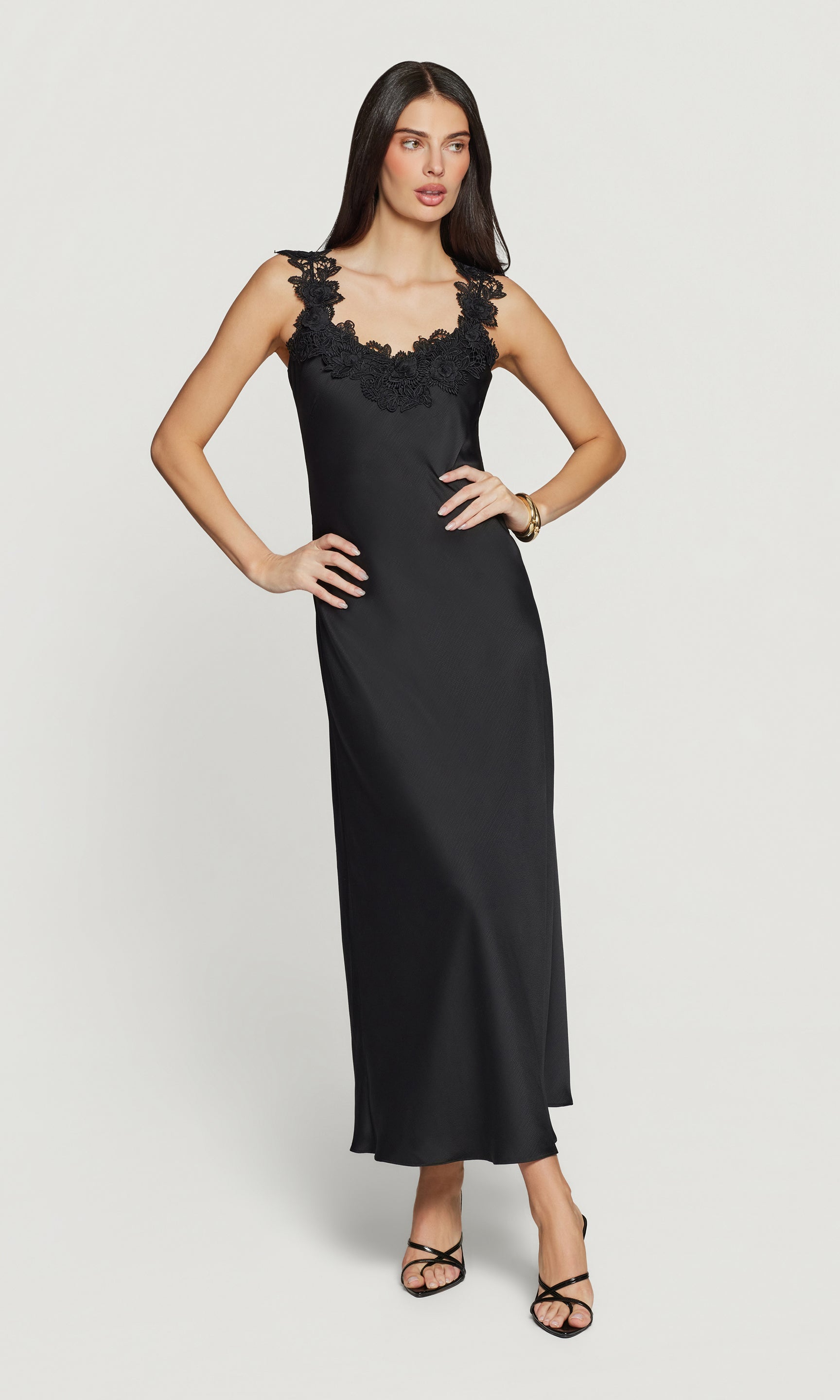 Woman wearing a black evening gown with lace details on a white background