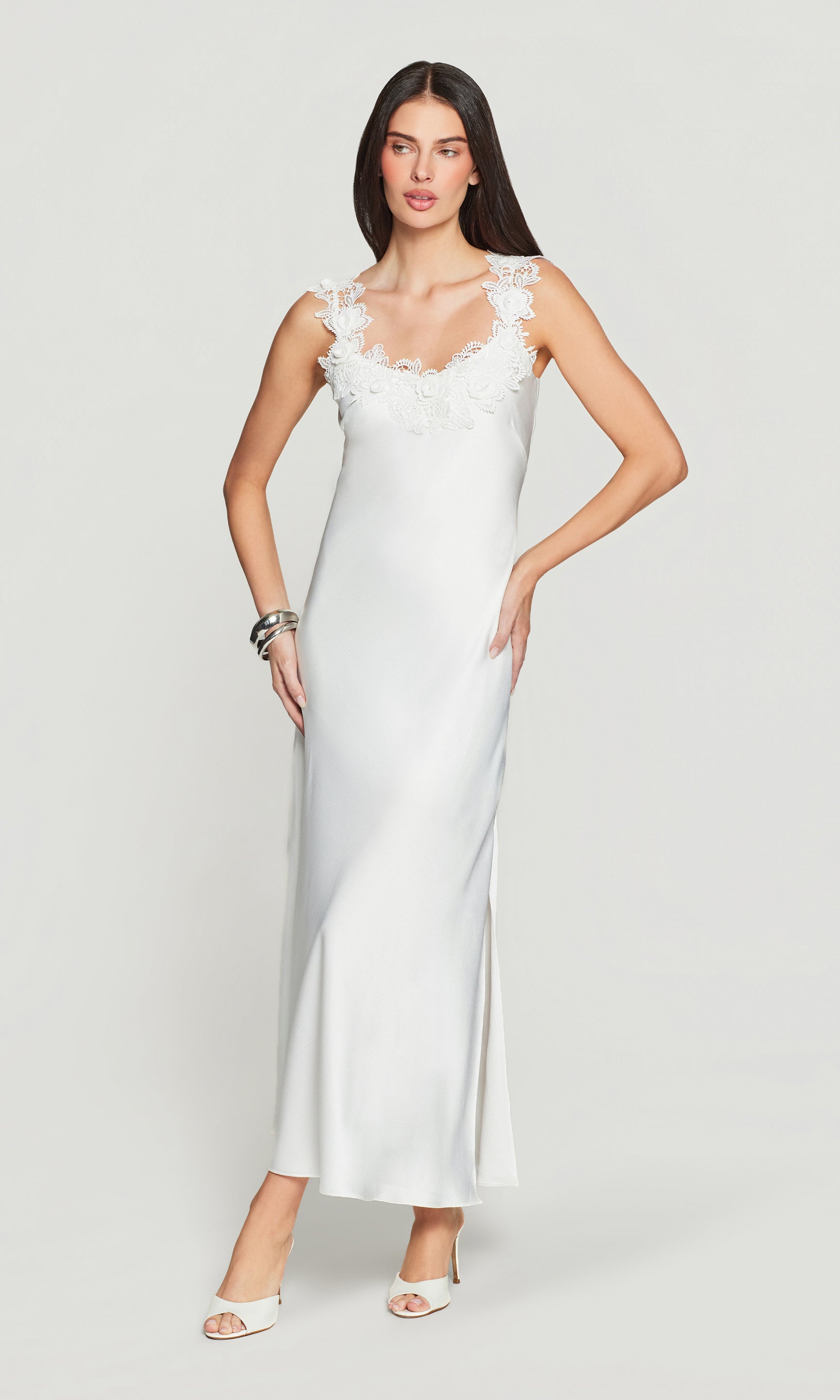 Woman wearing a white slip dress on a plain background
