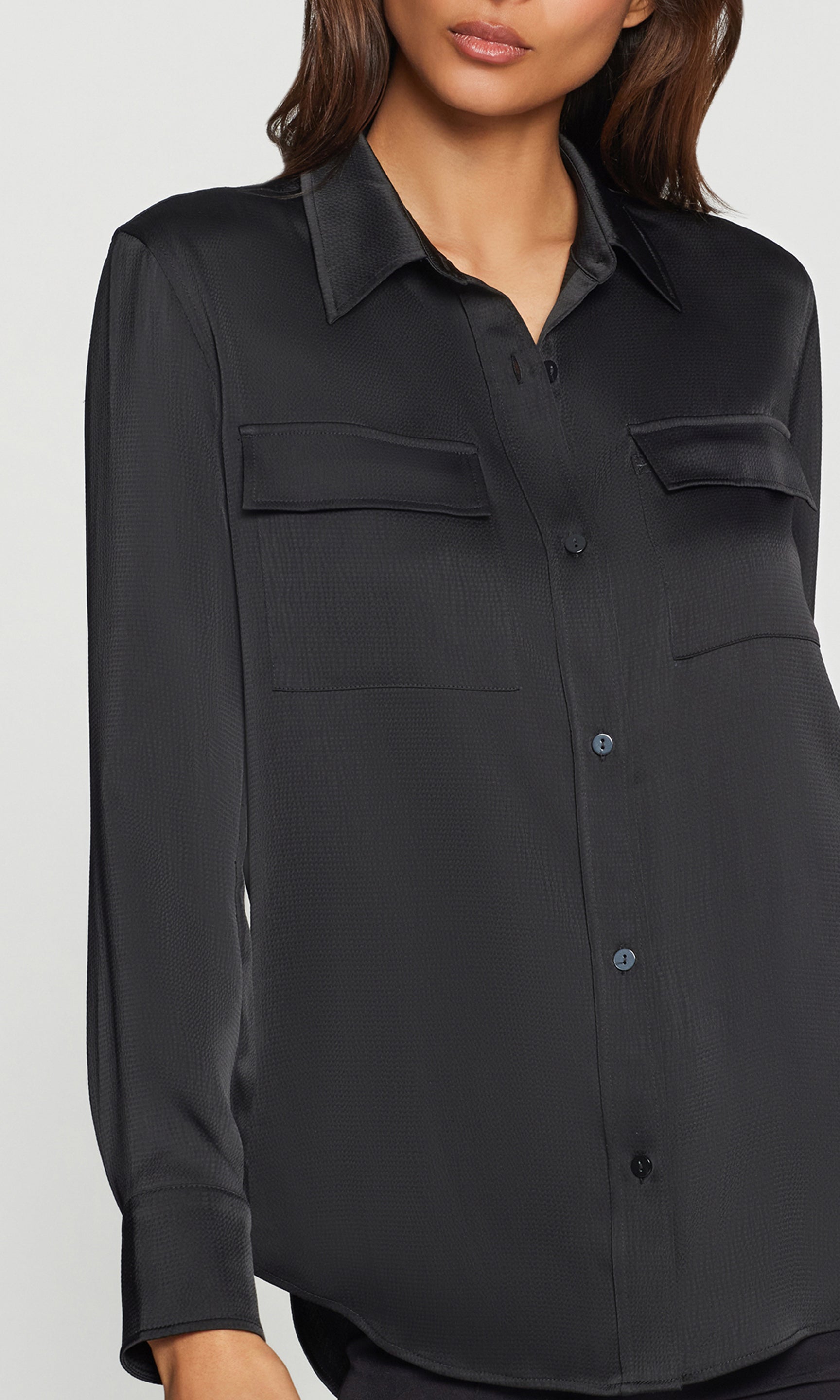 Close-up of black satin shirt worn by a person on a white background