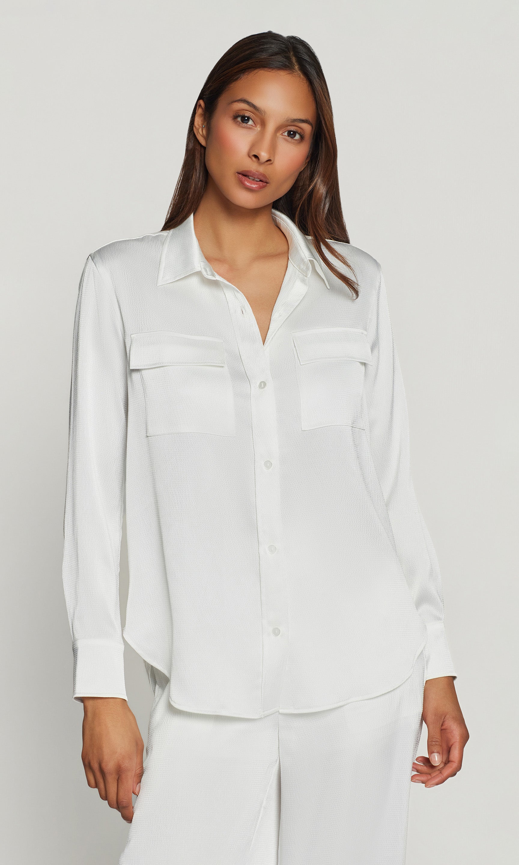 Woman wearing a white satin shirt against a plain background