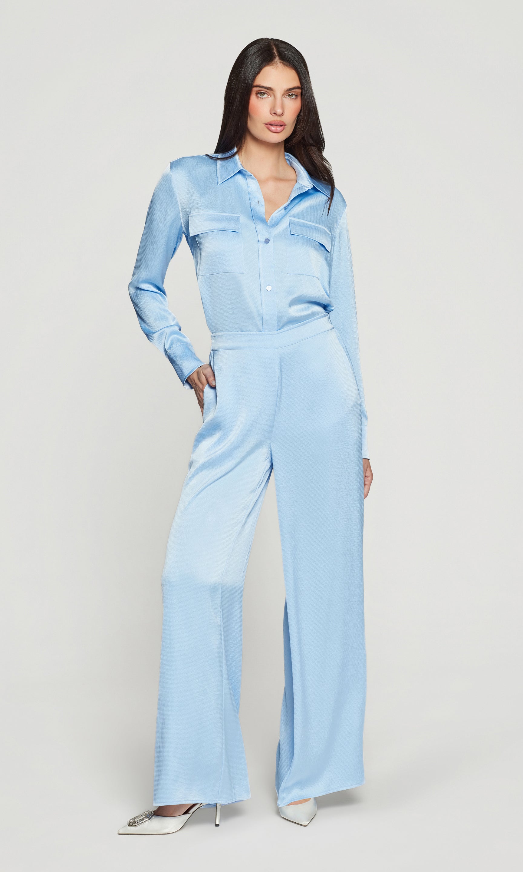 Woman wearing a light blue shirt and matching pants on a plain background