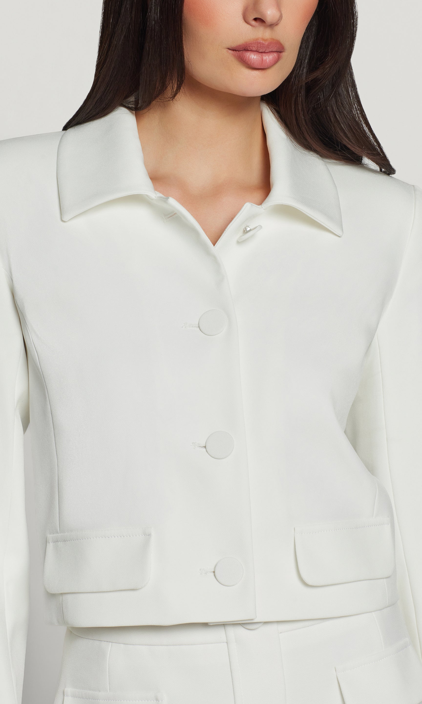Close-up of a person wearing a white jacket with a plain background