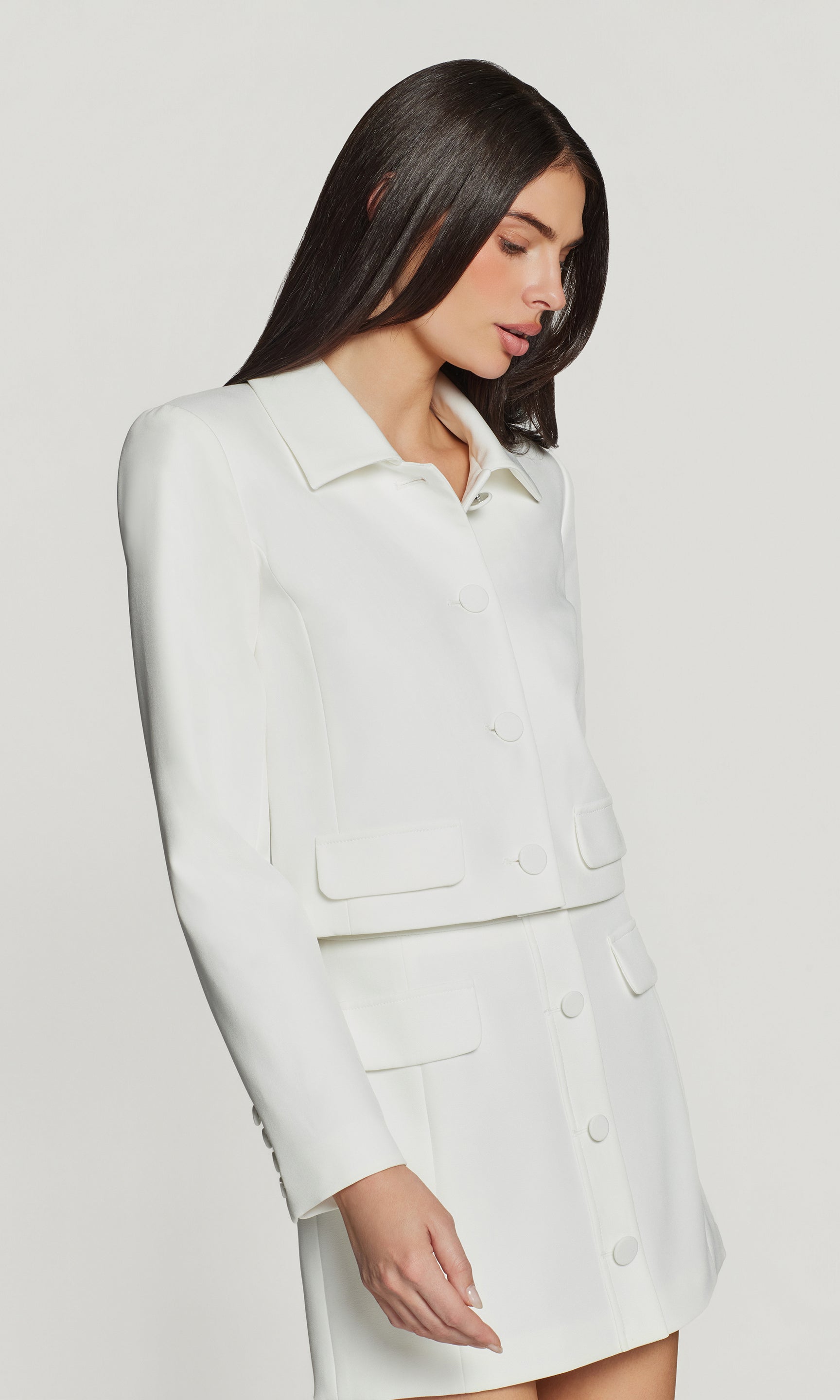 Side view of woman wearing a white suit on a plain background