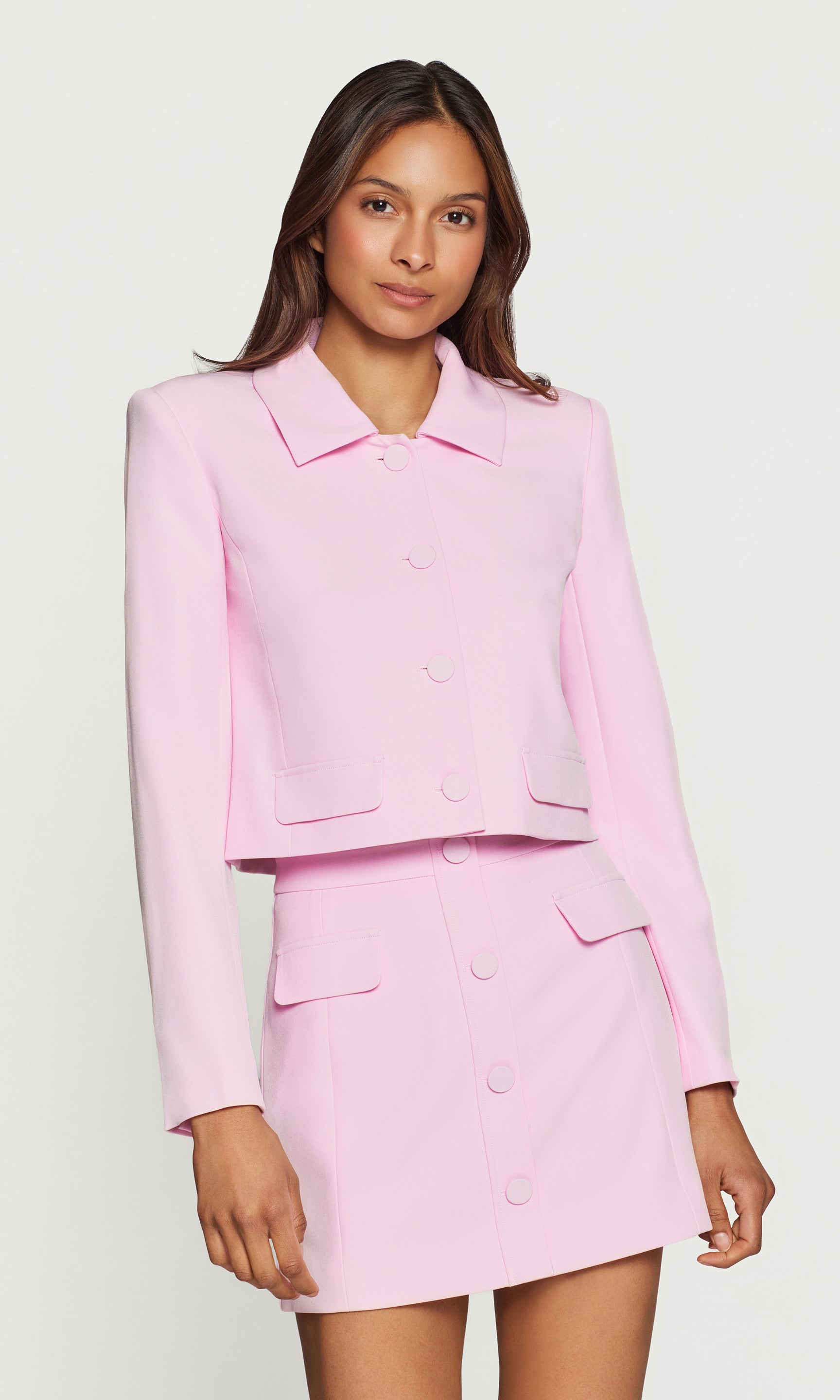 In a studio front view, the model wears the Luella Crepe Jacket in light pink, finished with a sharp collar, cropped hem, and matching covered buttons.