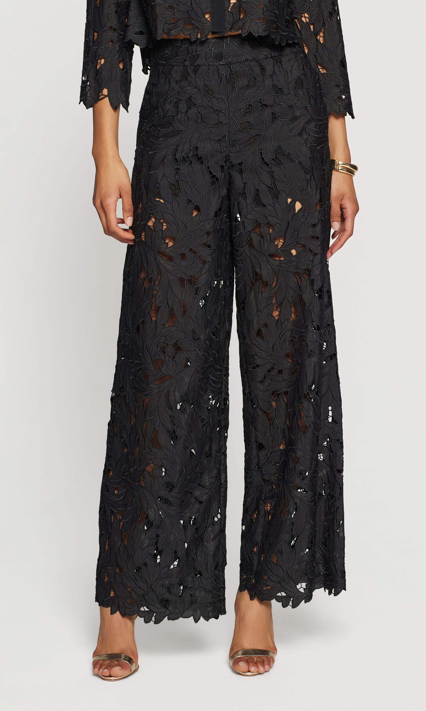 Black lace pants worn by a person on a white background