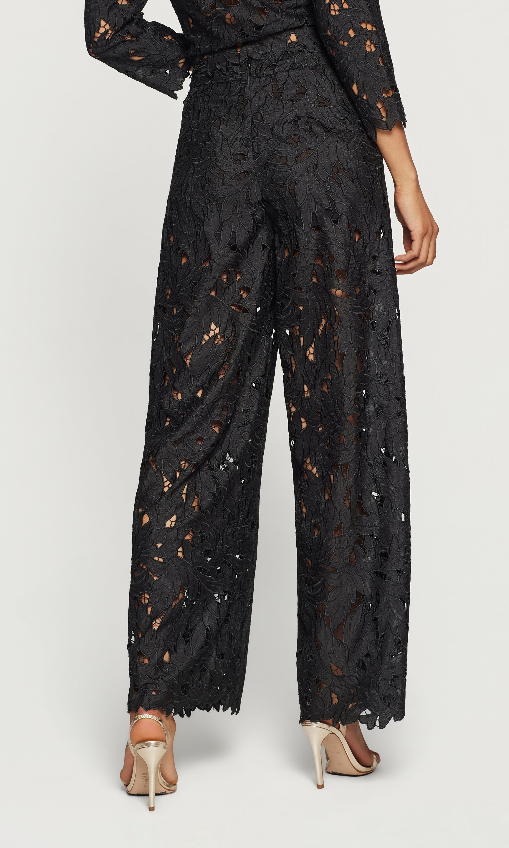 Back view of black lace pants worn by a person on a white background