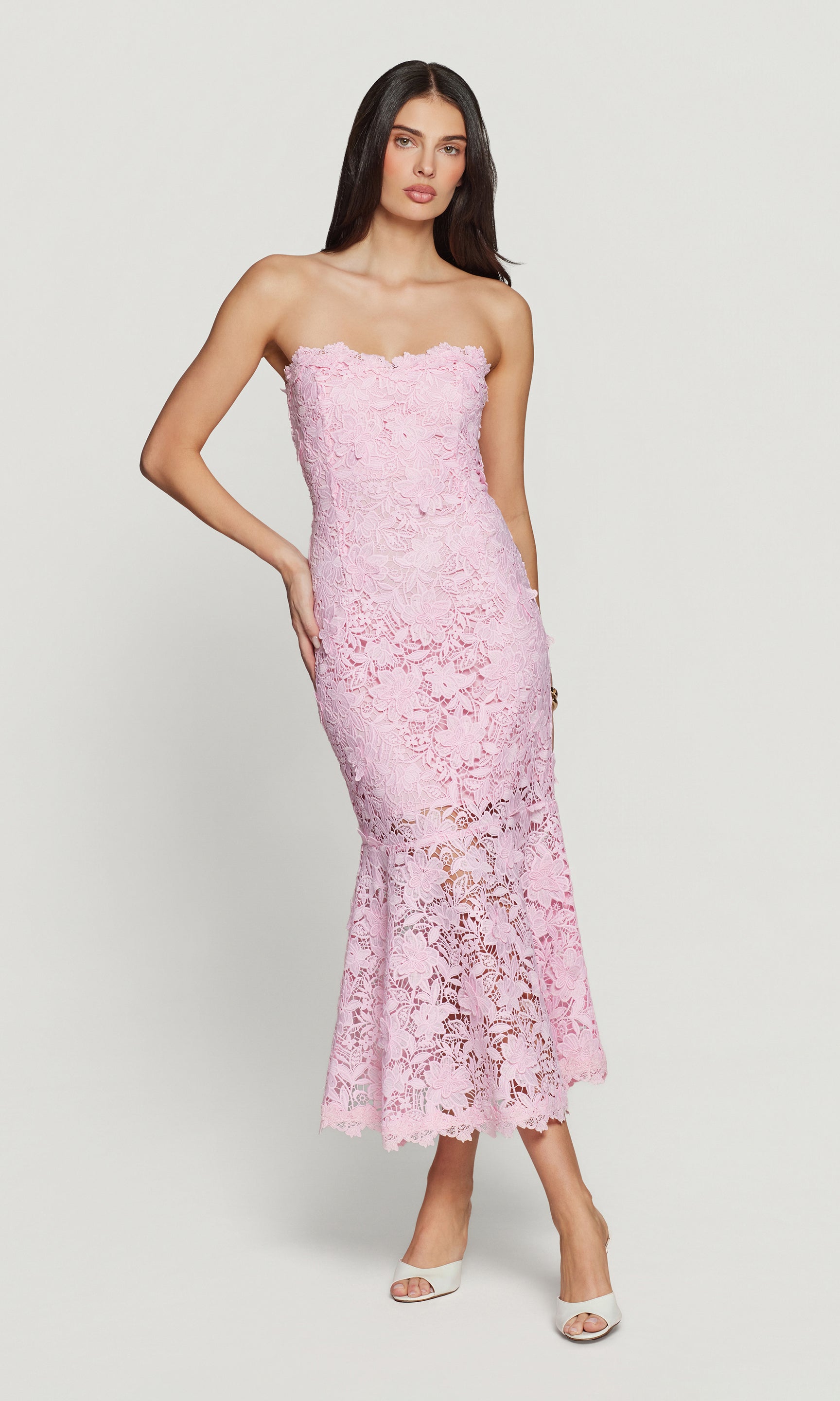 Woman wearing a pink strapless lace dress on a white background