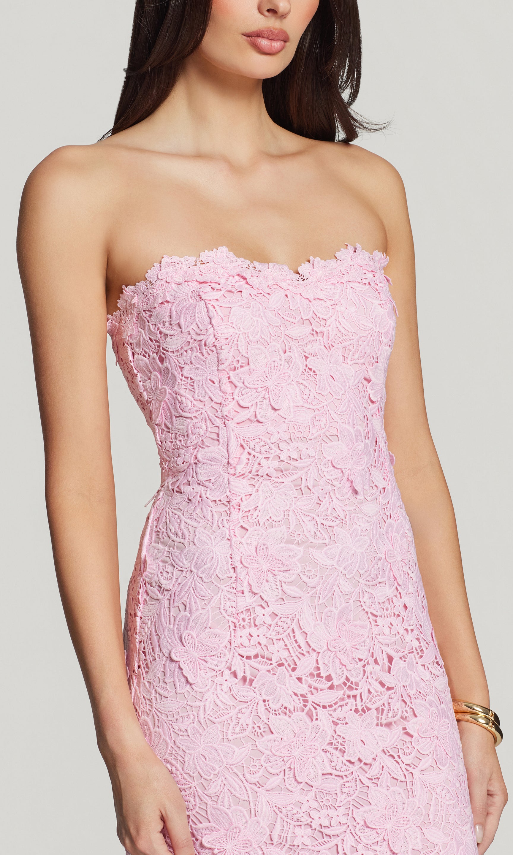 Close-up of pink strapless lace dress on a plain background