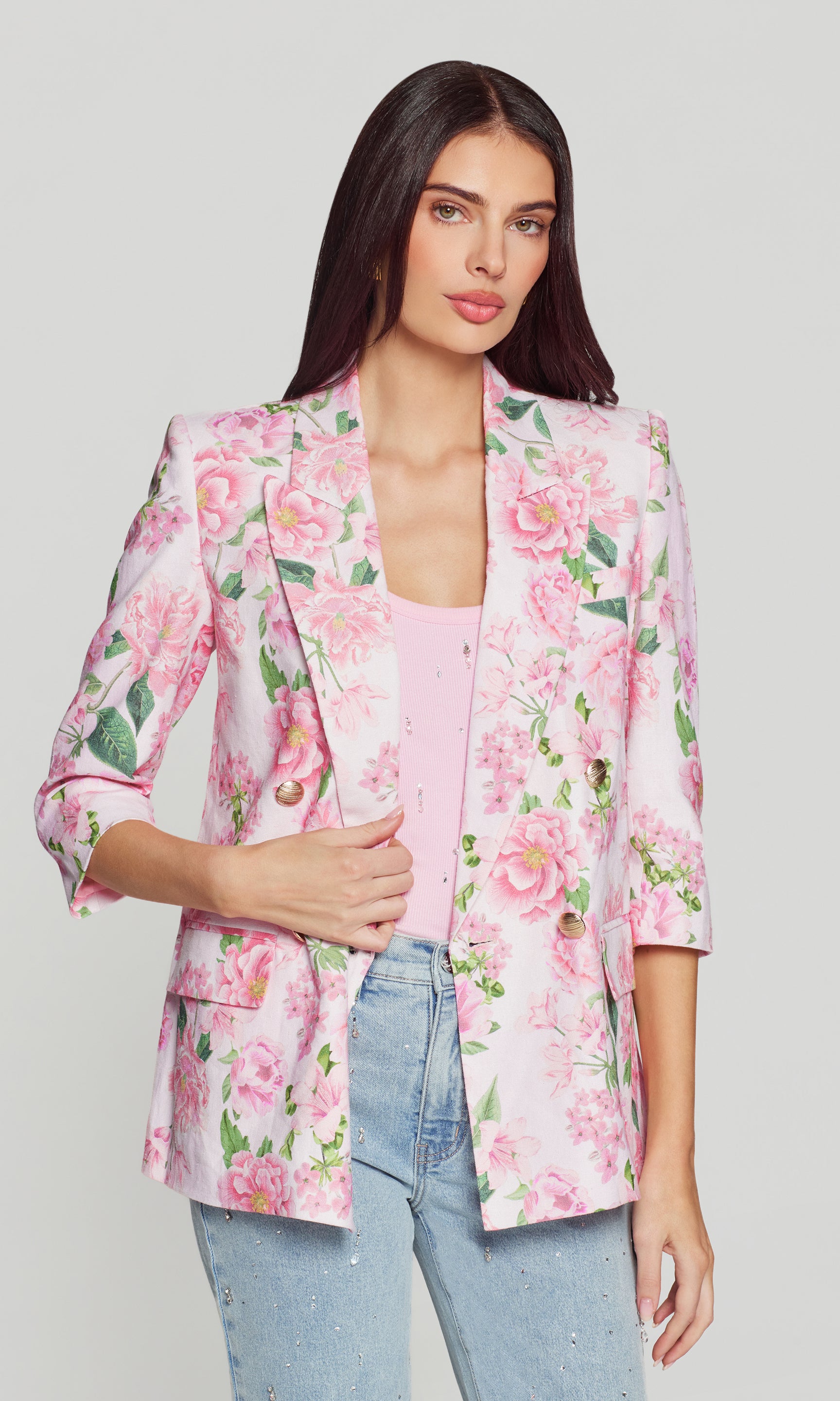 Woman wearing a pink floral blazer on a plain background