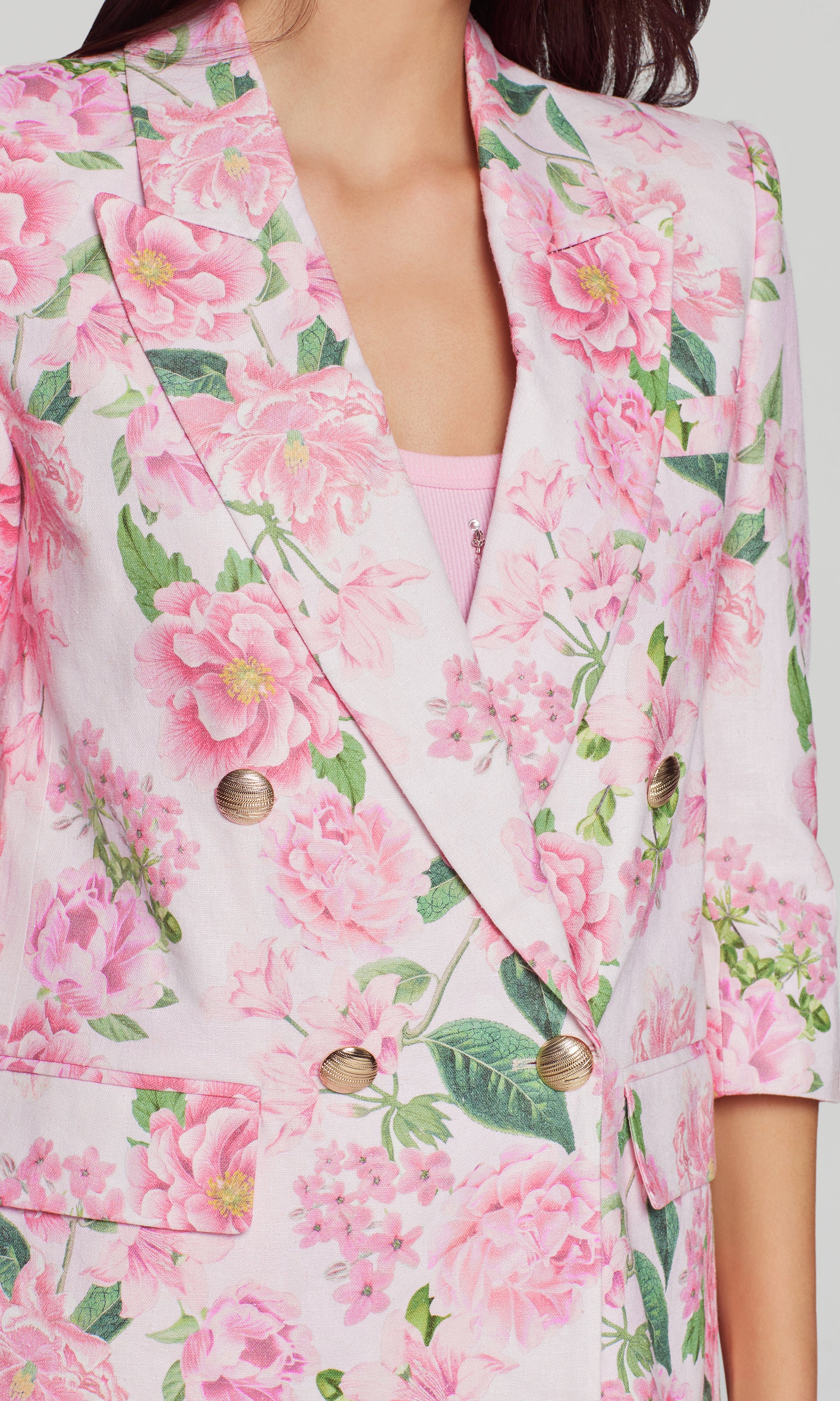 Close-up of floral patterned blazer with pink flowers and green leaves on a white background