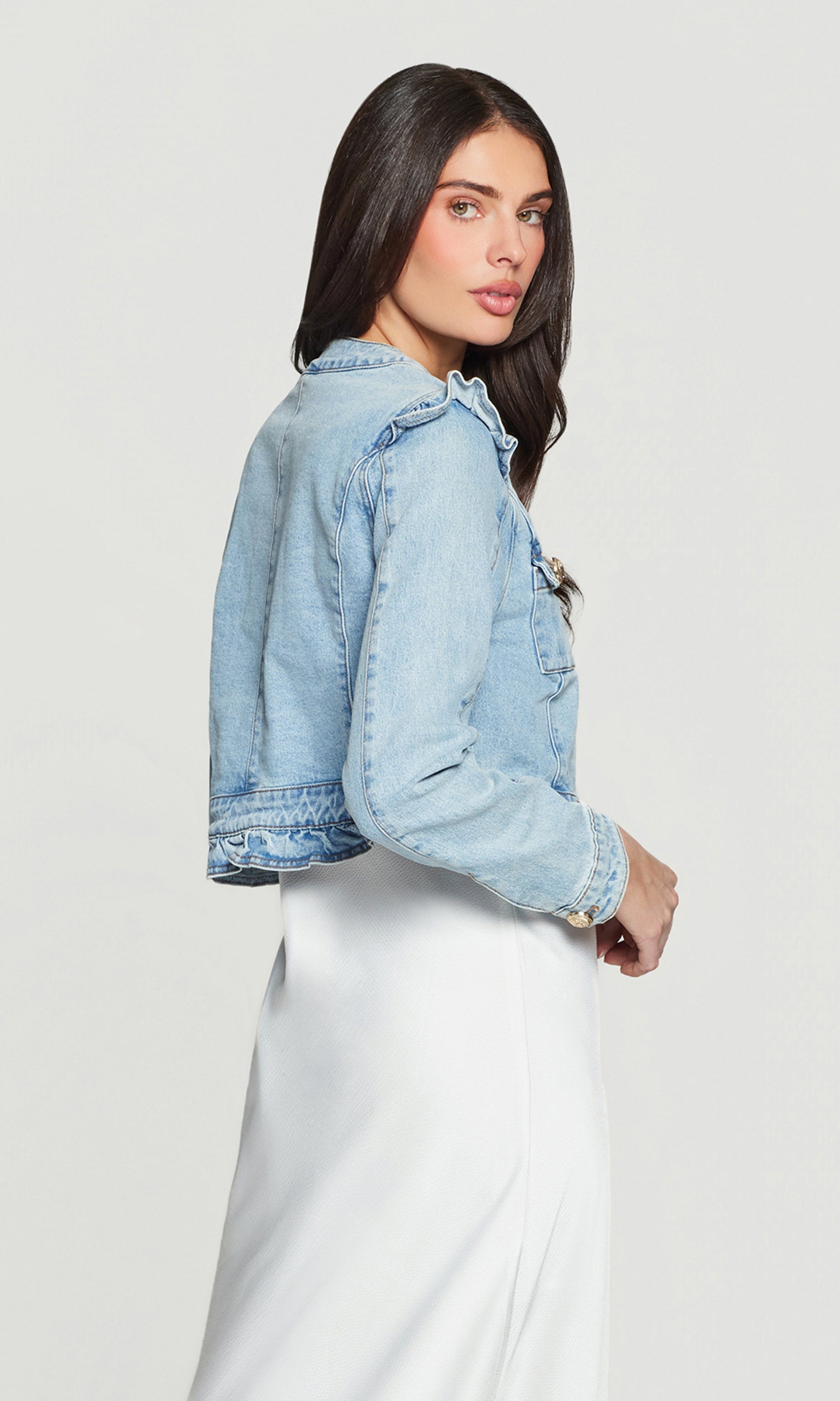 Side view of woman wearing a light blue denim jacket on a white background